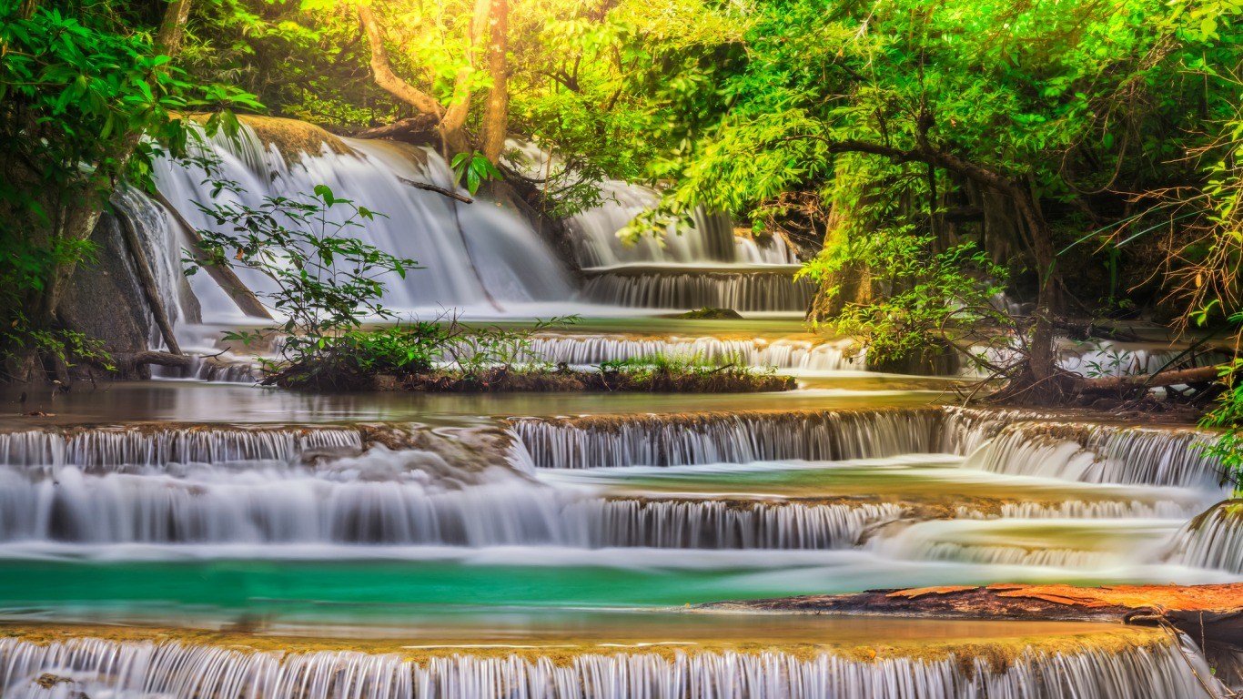 Tiered waterfall in a lush green forest HD Wallpaper