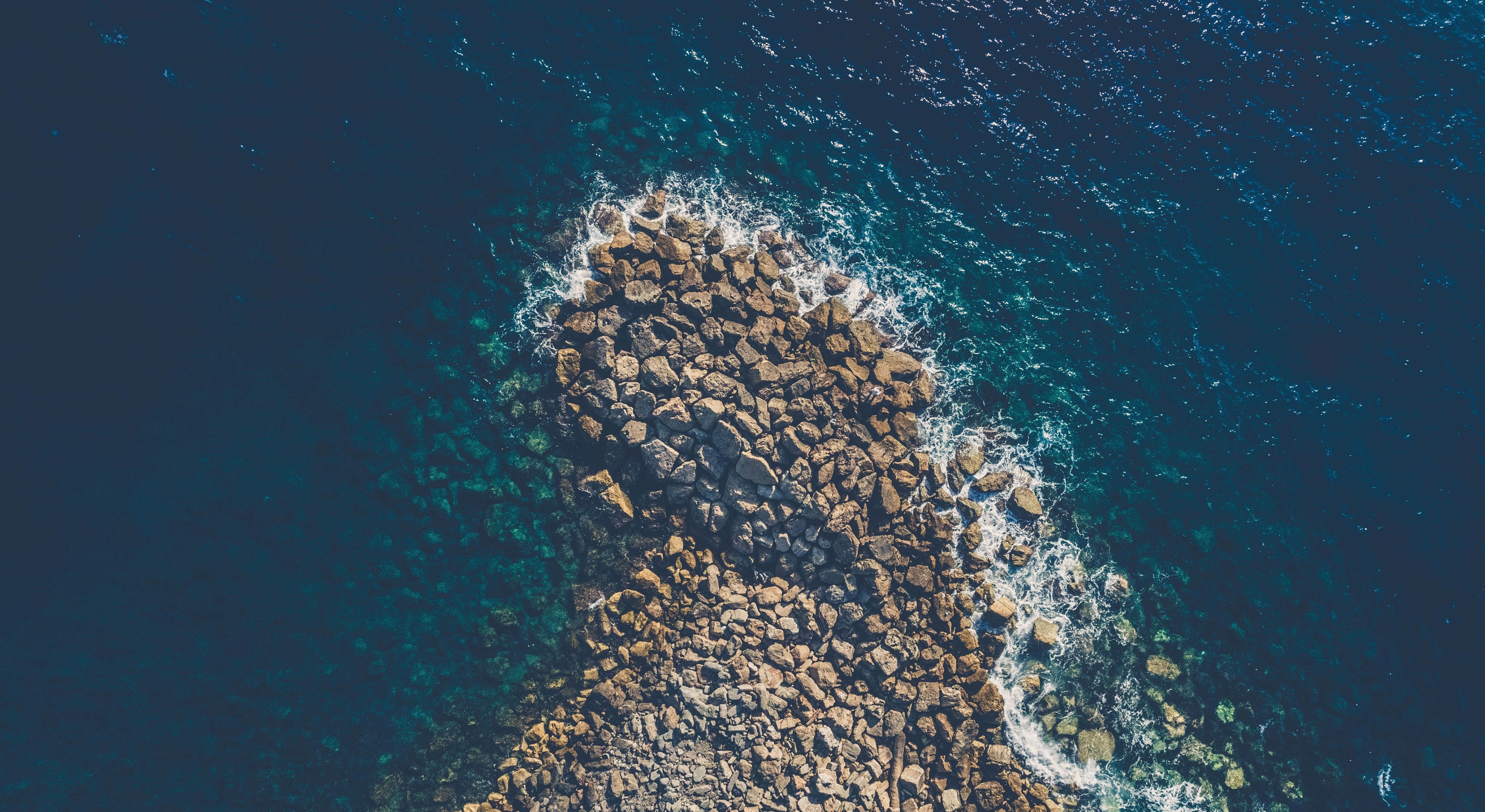 Aerial view of rocky coastline and deep blue ocean HD Wallpaper
