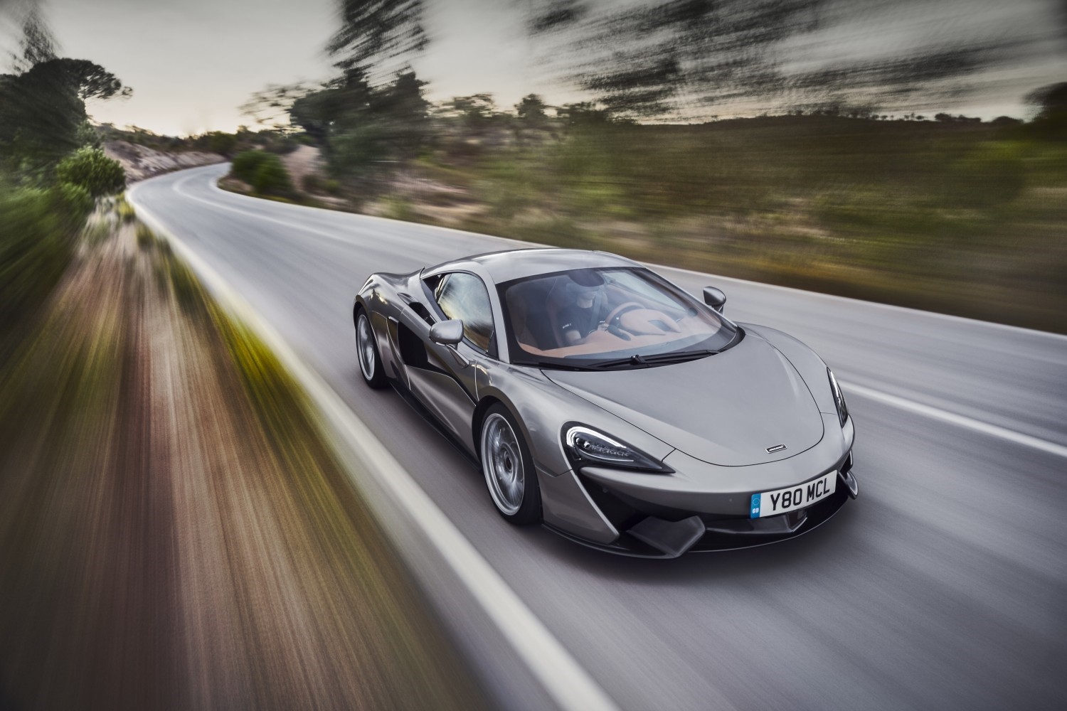 McLaren 570S driving on a winding road HD Wallpaper