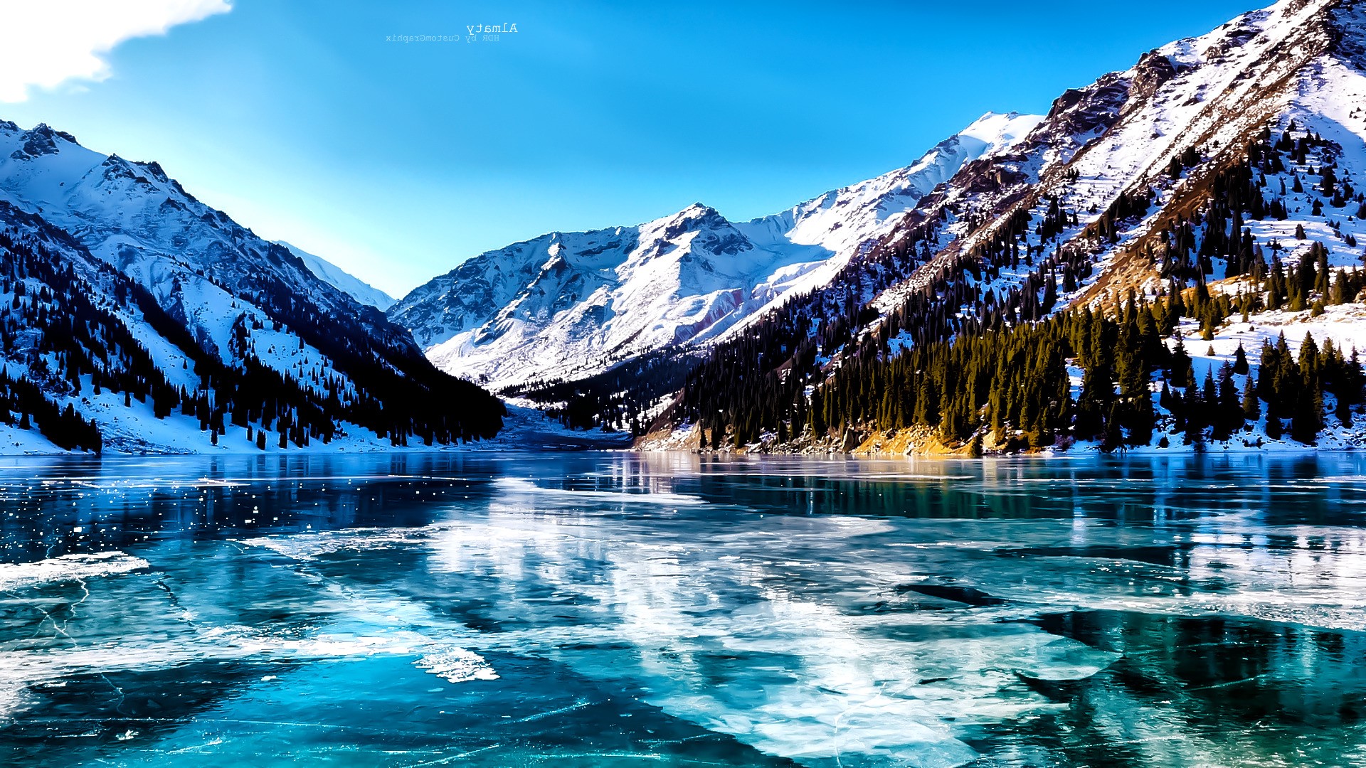 Frozen mountain lake with snow-covered peaks and pine trees HD Wallpaper