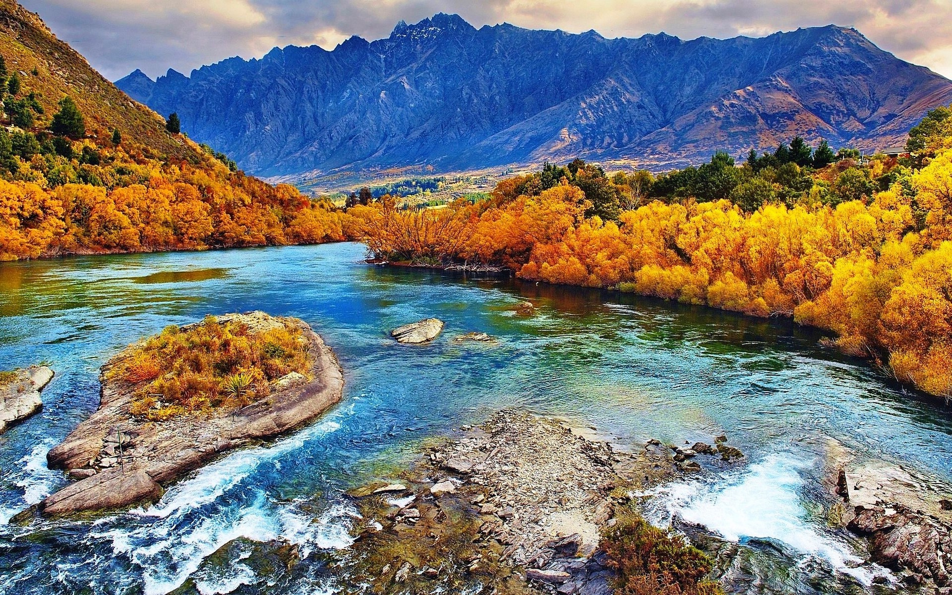River flowing through autumn forest with mountains HD Wallpaper