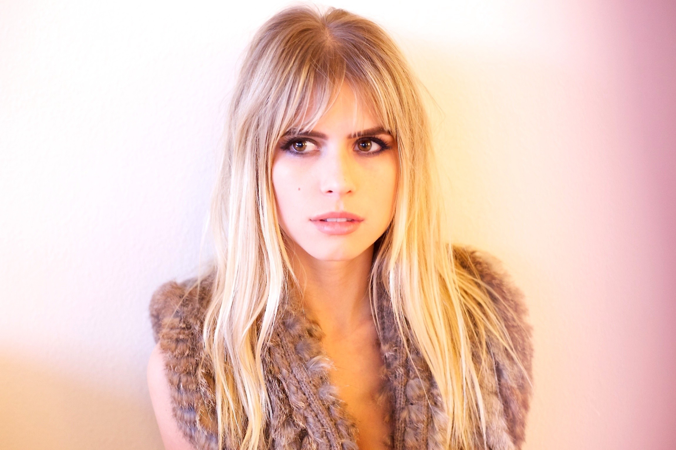 Young blonde woman wearing a fur vest HD Wallpaper