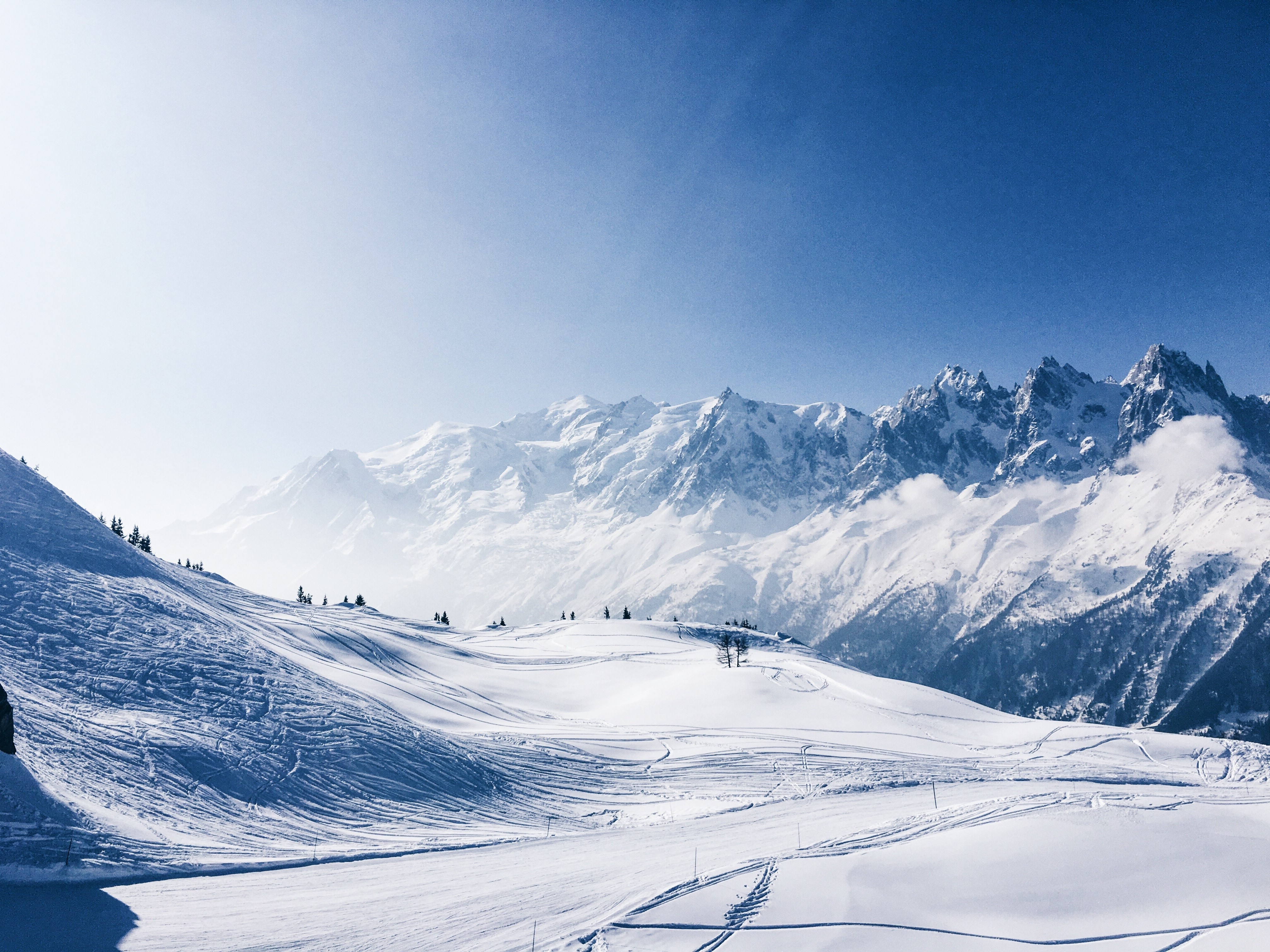 Snowy mountains and ski slopes under a clear blue sky HD Wallpaper
