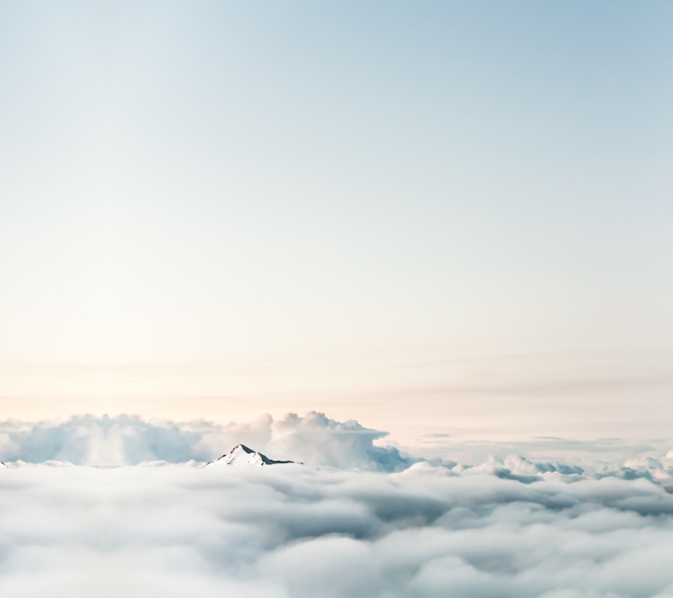 Snow-capped mountain peak above clouds at sunrise HD Wallpaper