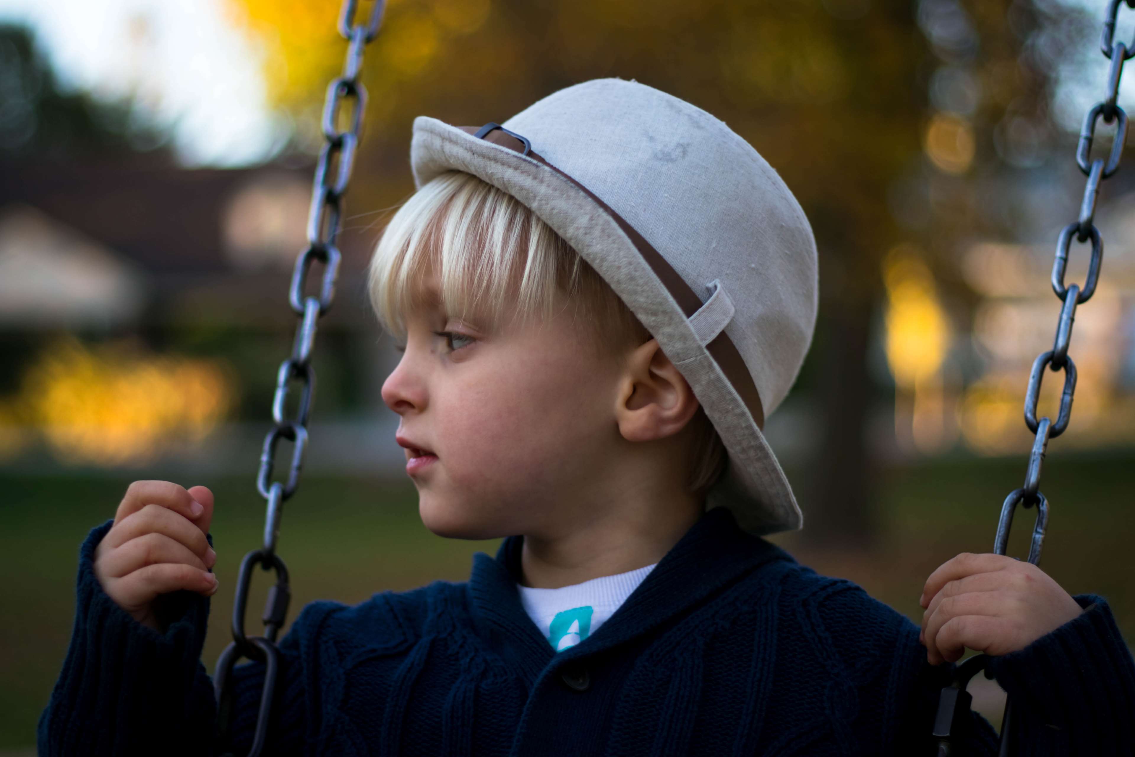 Boy in hat on a swing HD Wallpaper