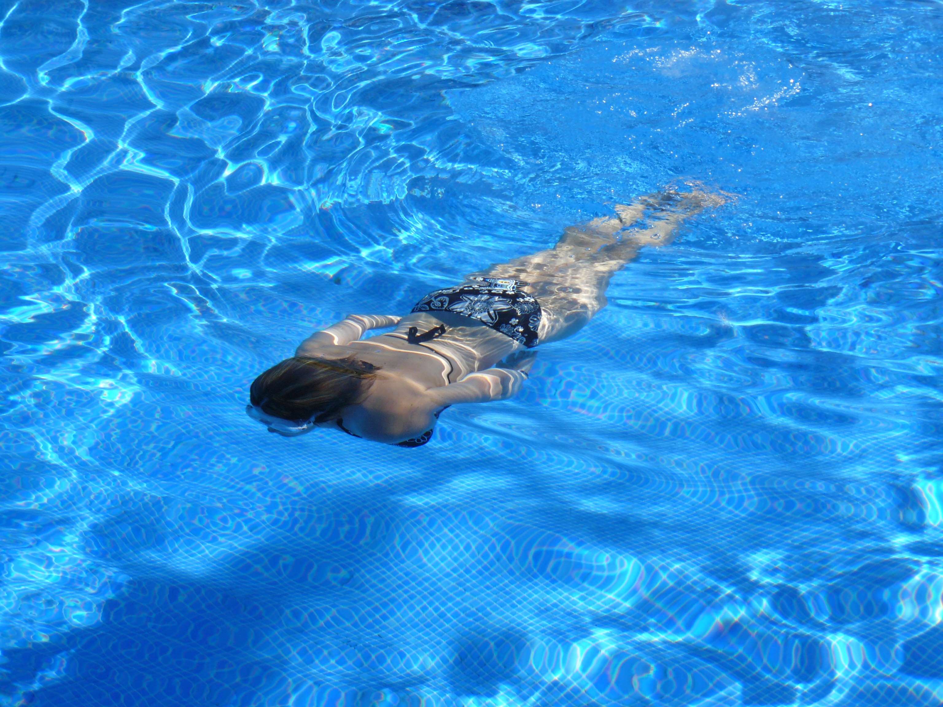 Woman swimming underwater in a blue swimming pool HD Wallpaper