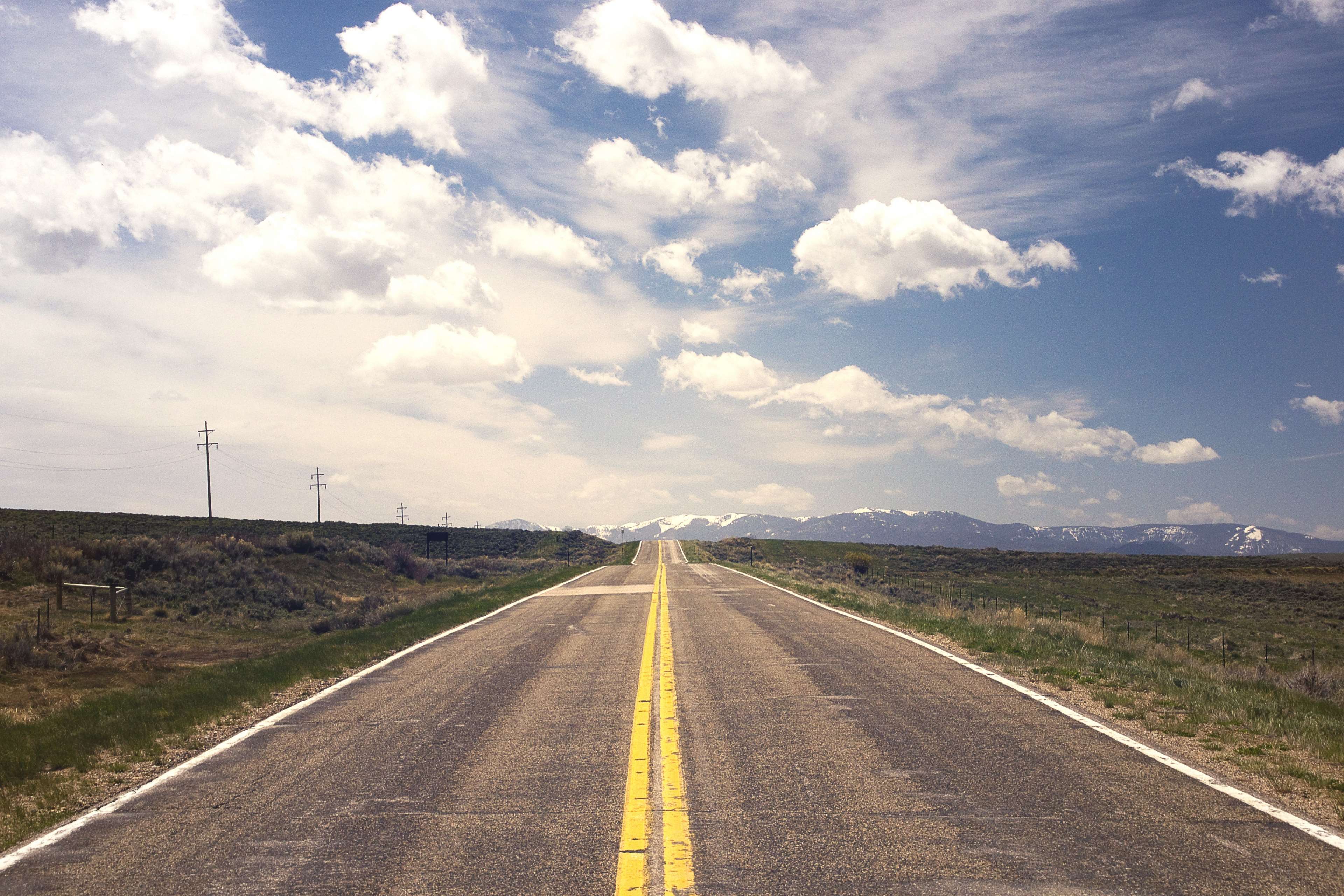 Endless highway through a vast landscape with mountains HD Wallpaper