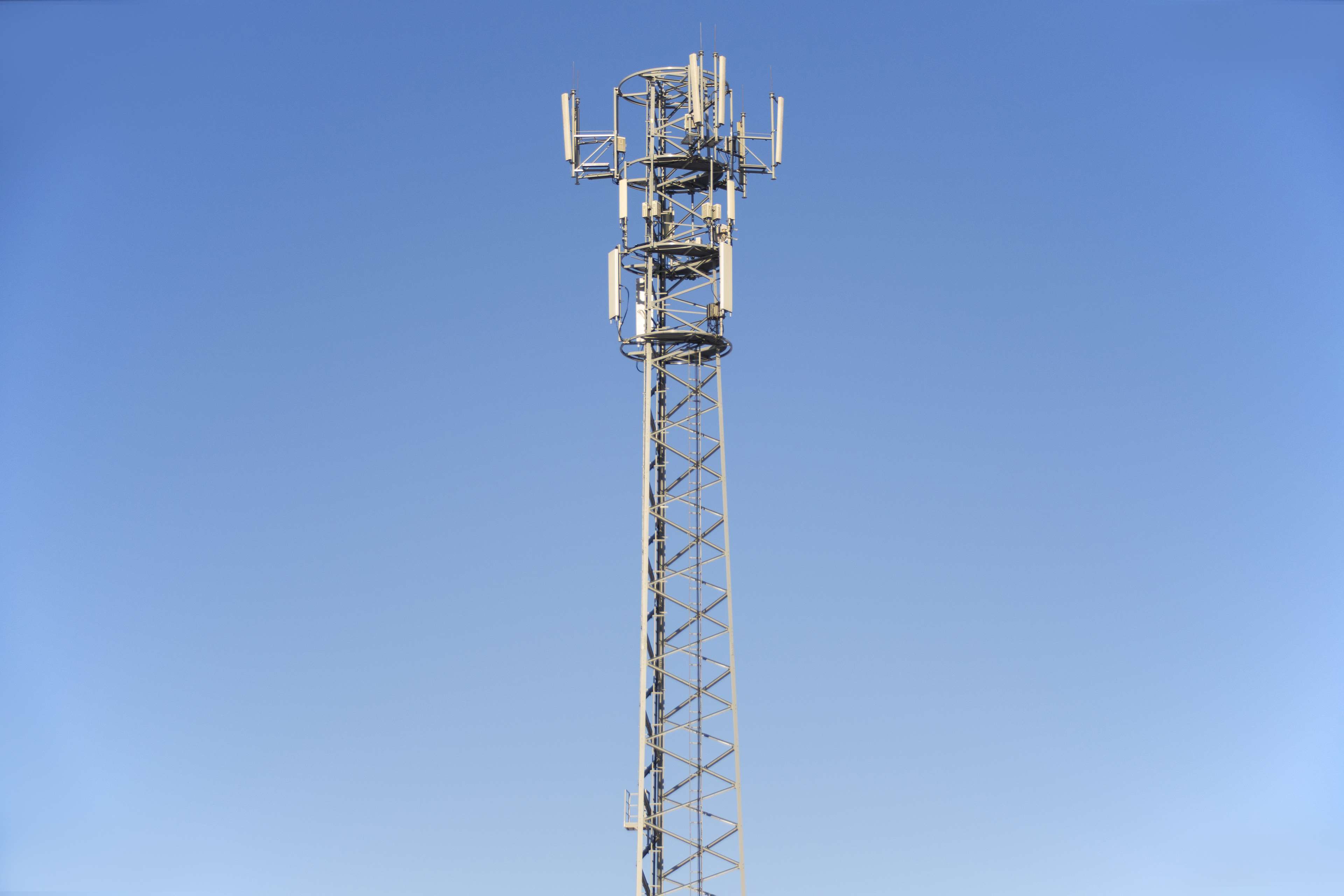 Cell tower with antennas against a clear blue sky HD Wallpaper