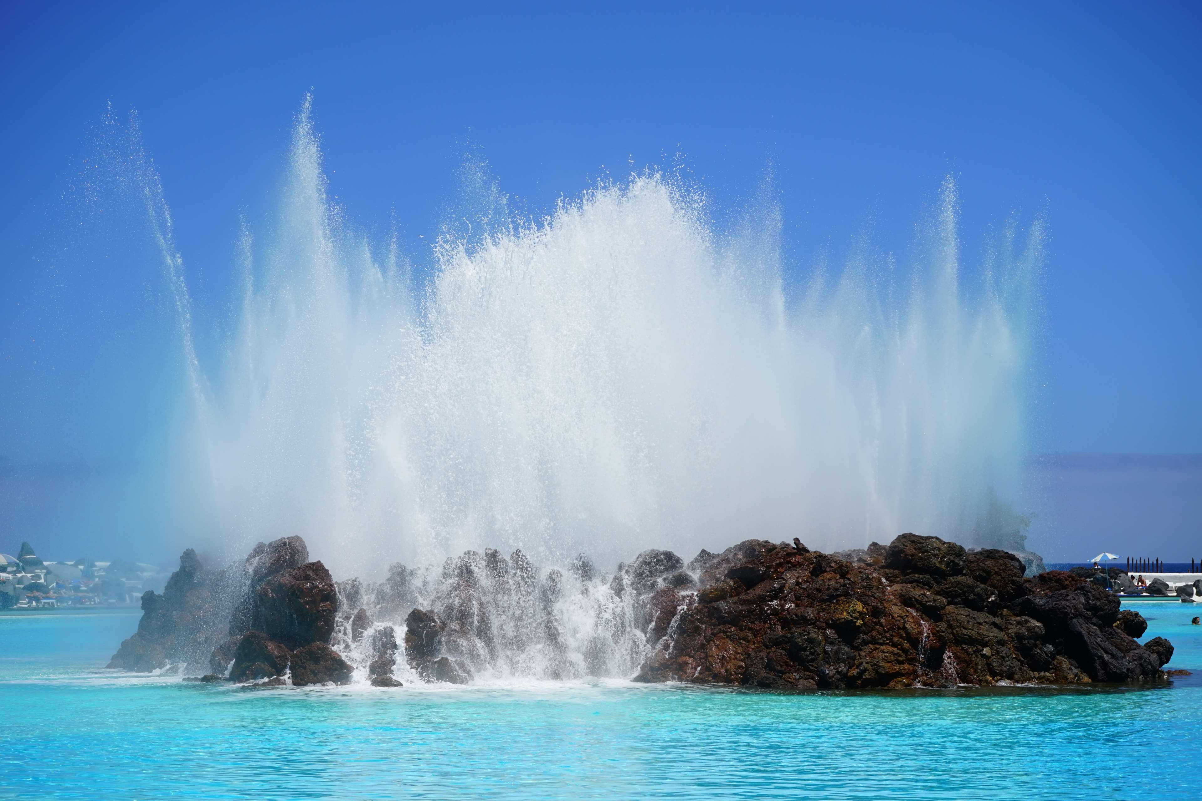 Large water fountain erupting from rocks in the ocean HD Wallpaper