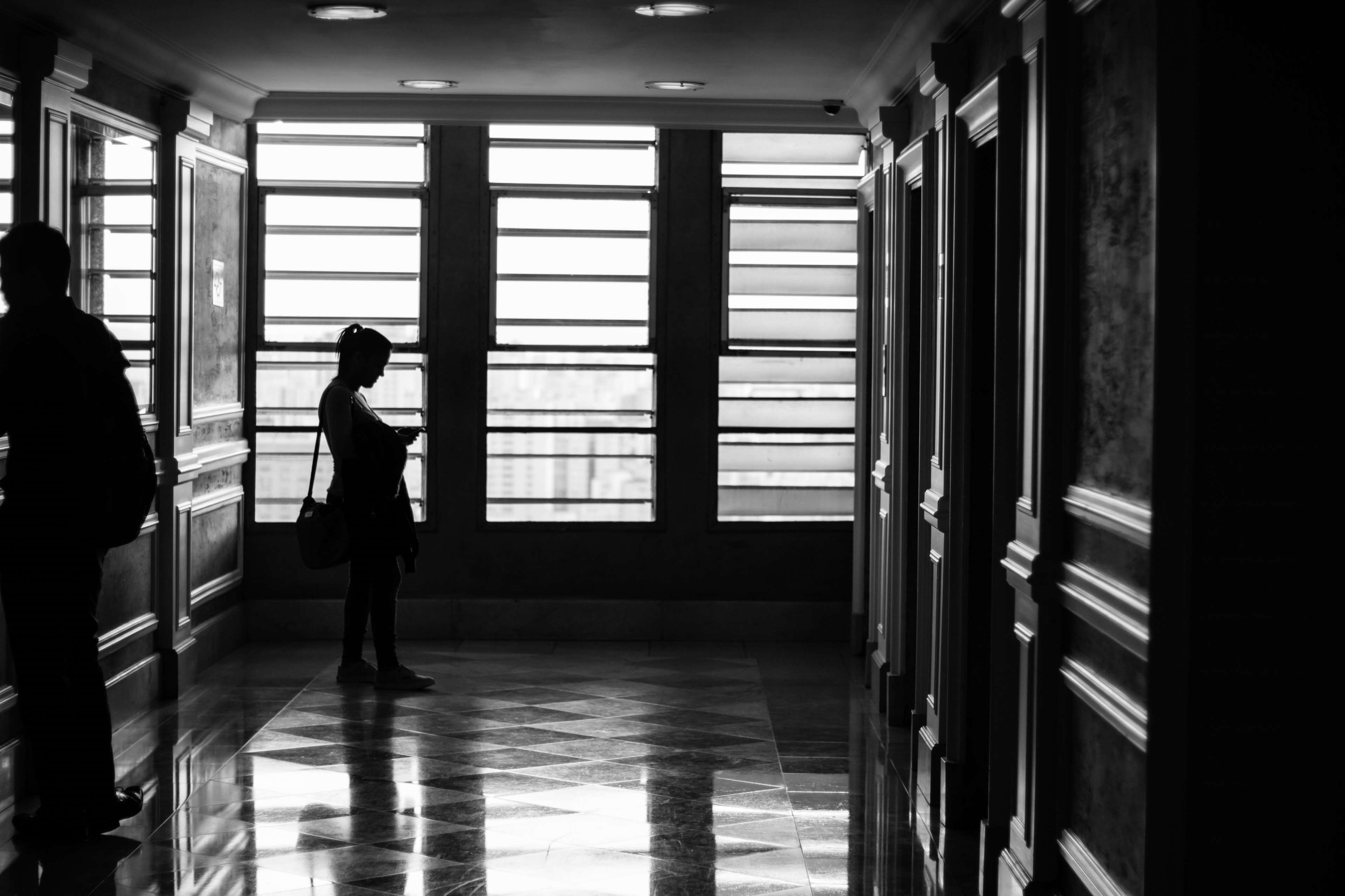 People in a dark hallway with large windows HD Wallpaper