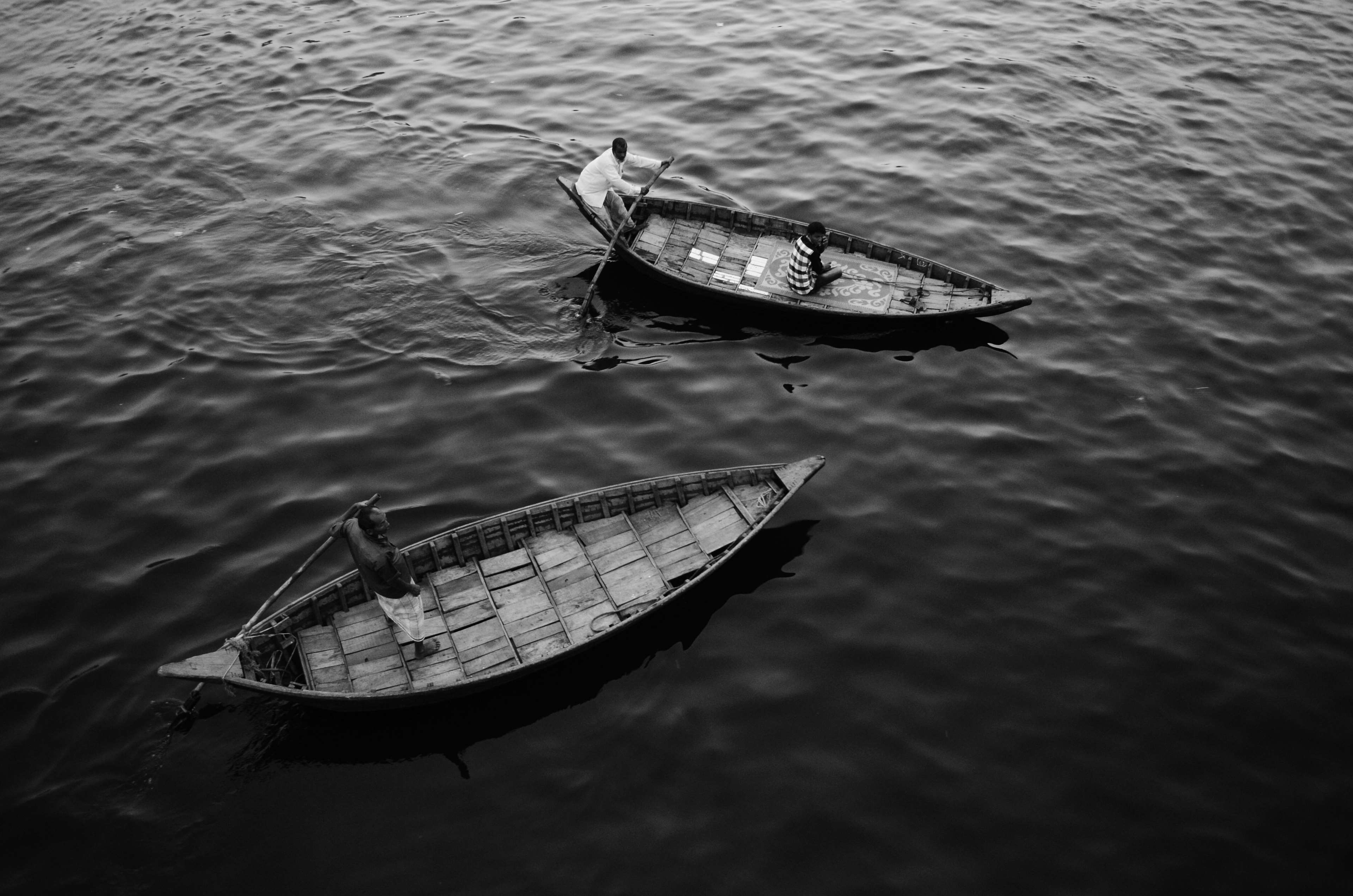 Two boats with people rowing on a dark body of water HD Wallpaper