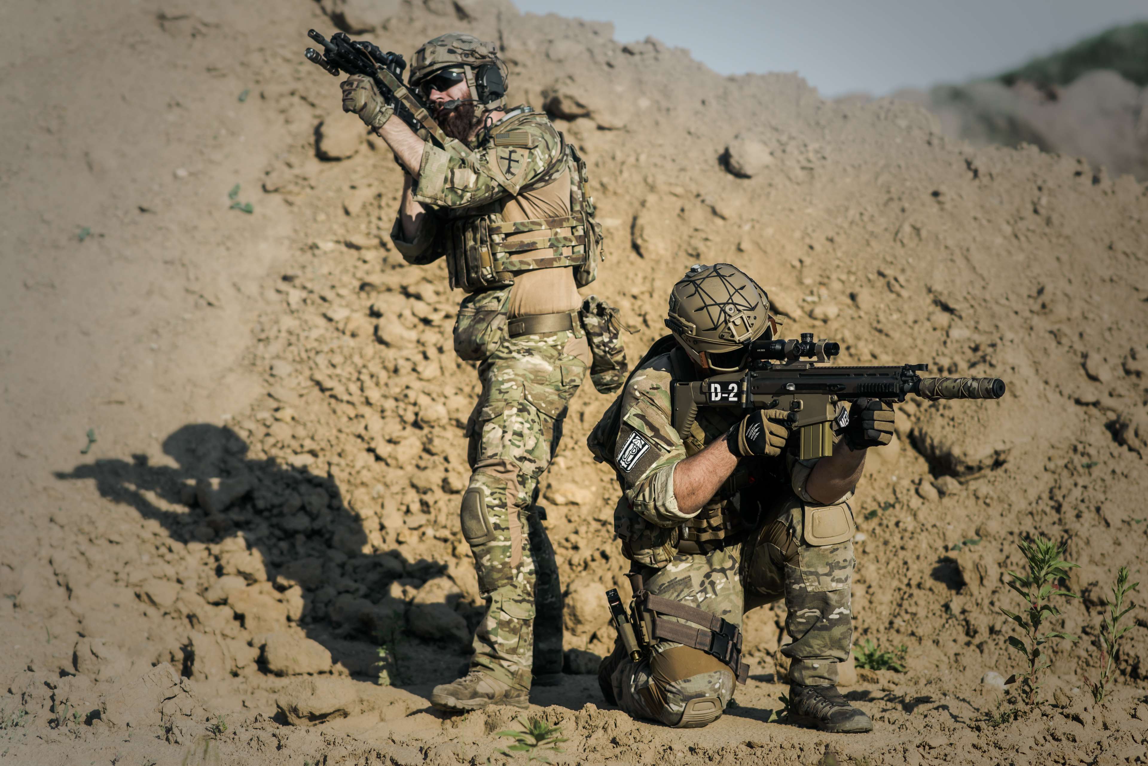 Two soldiers in camouflage with rifles in a desert HD Wallpaper