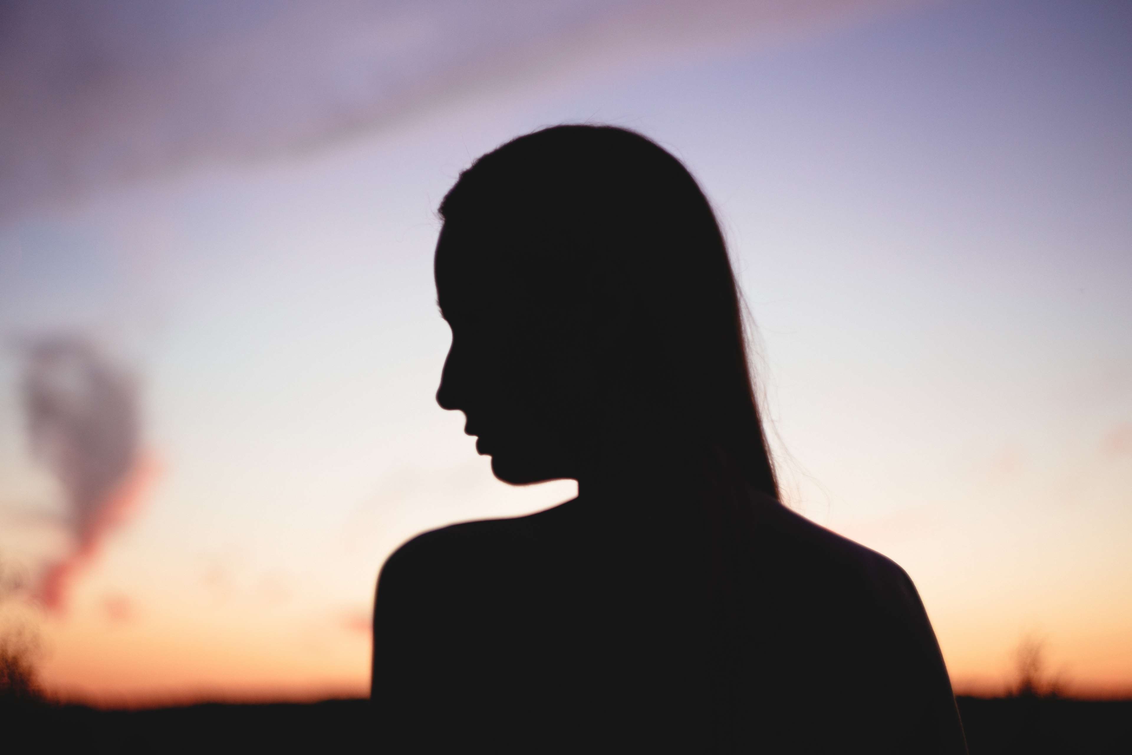Silhouette of a woman against a sunset sky HD Wallpaper