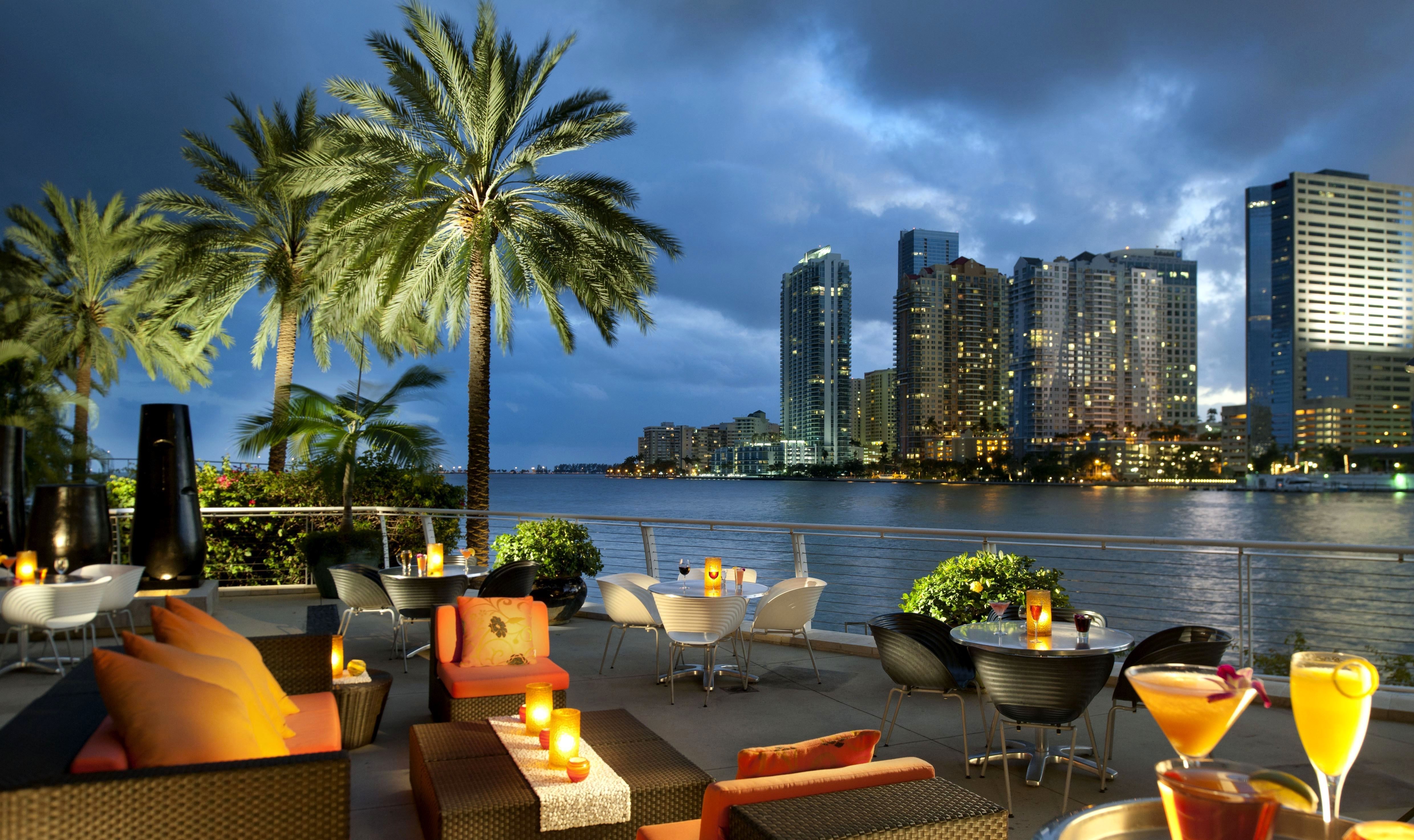Outdoor restaurant seating with Miami skyline at dusk HD Wallpaper