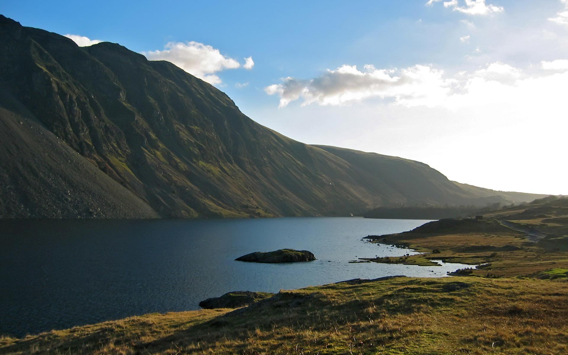 Mountain lake with rocky slopes and grassy shore HD Wallpaper