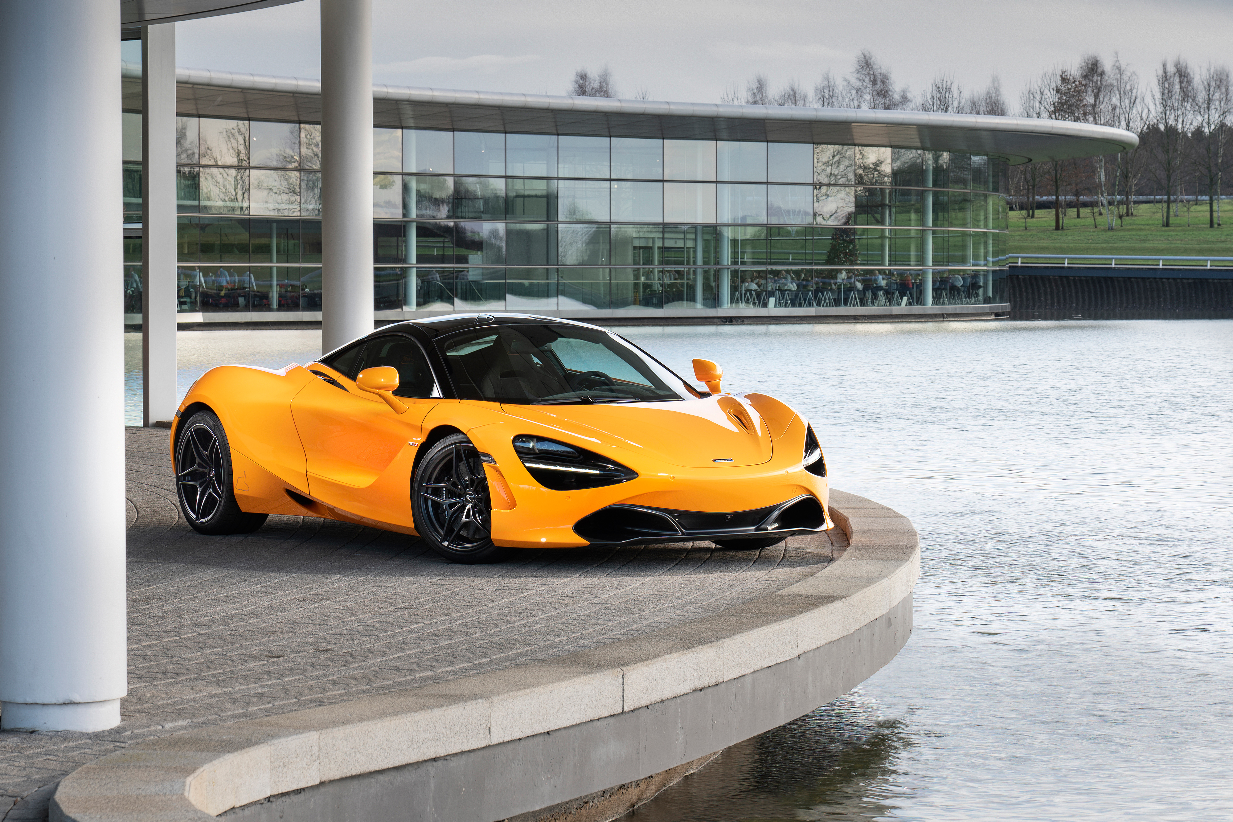 Orange McLaren 720S parked by a modern building HD Wallpaper