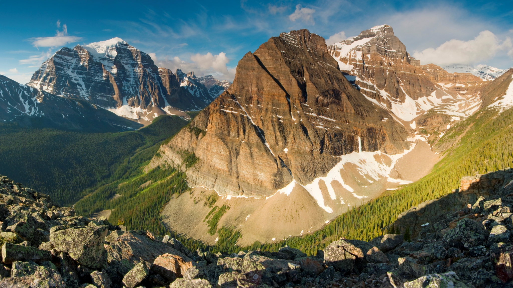 Rocky mountain range with snow-capped peaks and green forest HD Wallpaper
