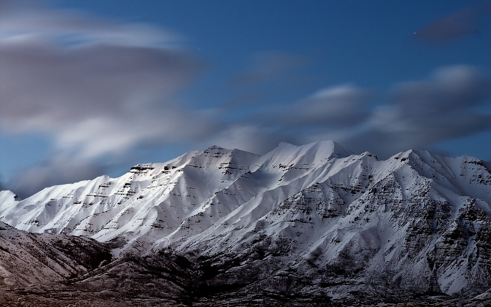 Snow-covered mountains under a cloudy blue sky HD Wallpaper