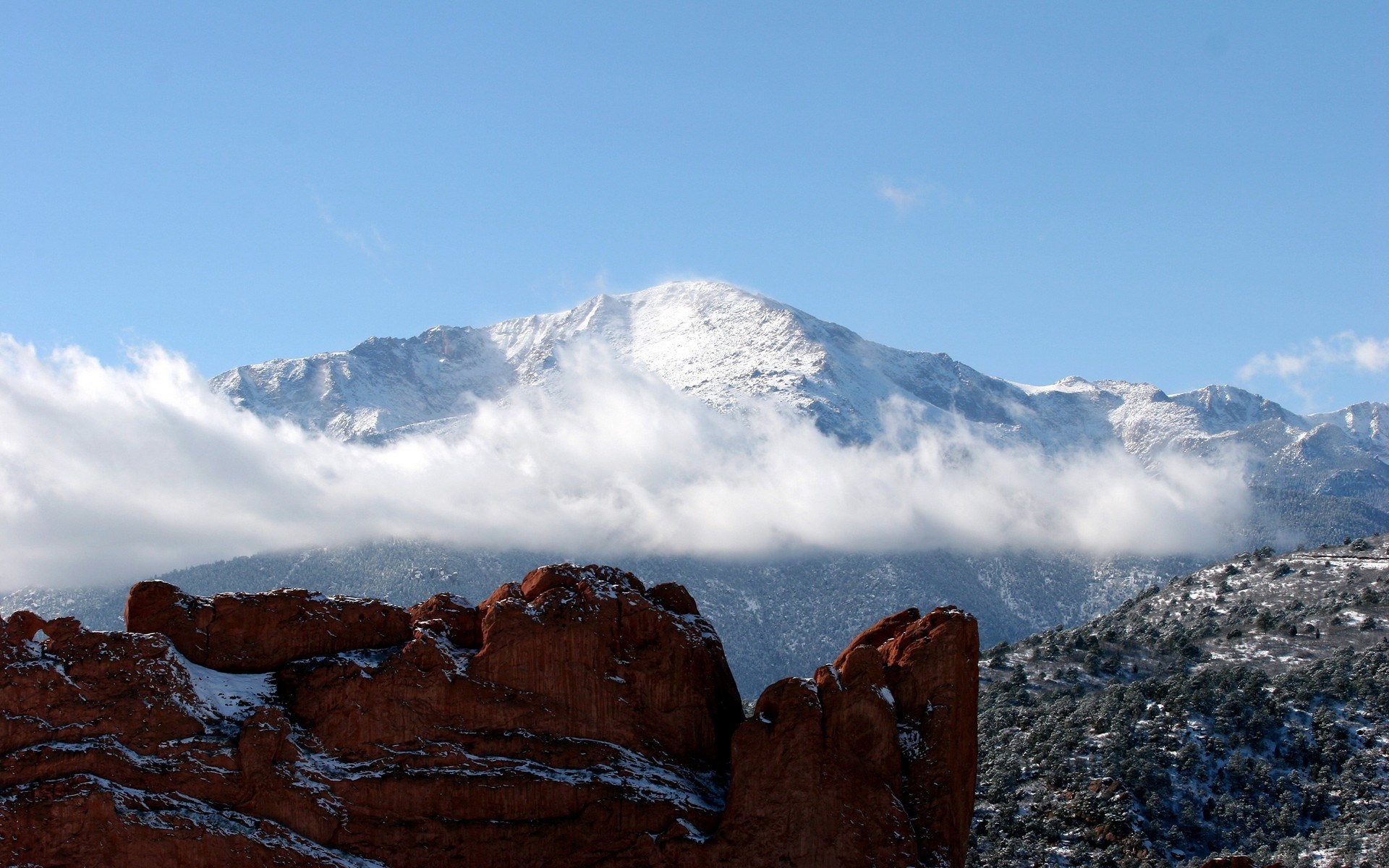Snow-capped mountain peak above red rocks and clouds HD Wallpaper