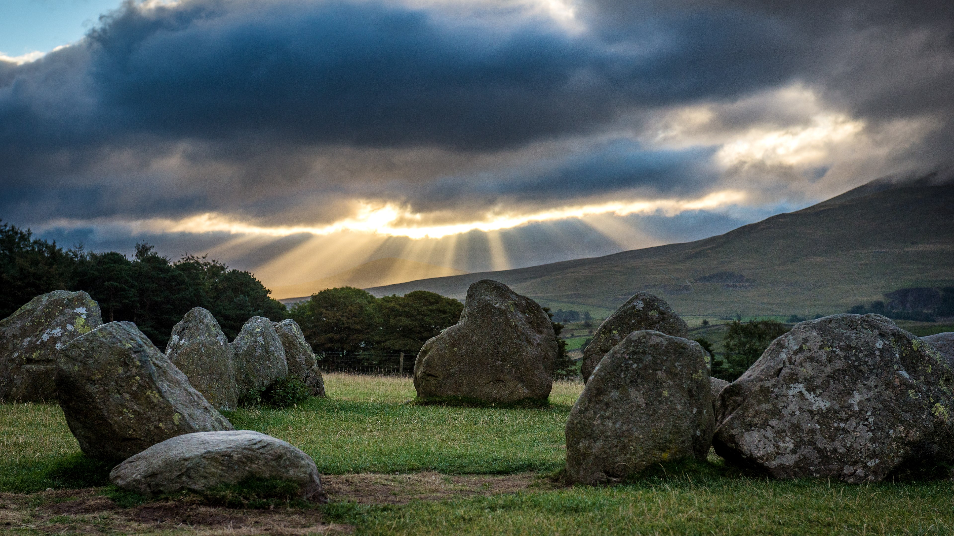 Stone Circle with Sunbeams and Mountains HD Wallpaper