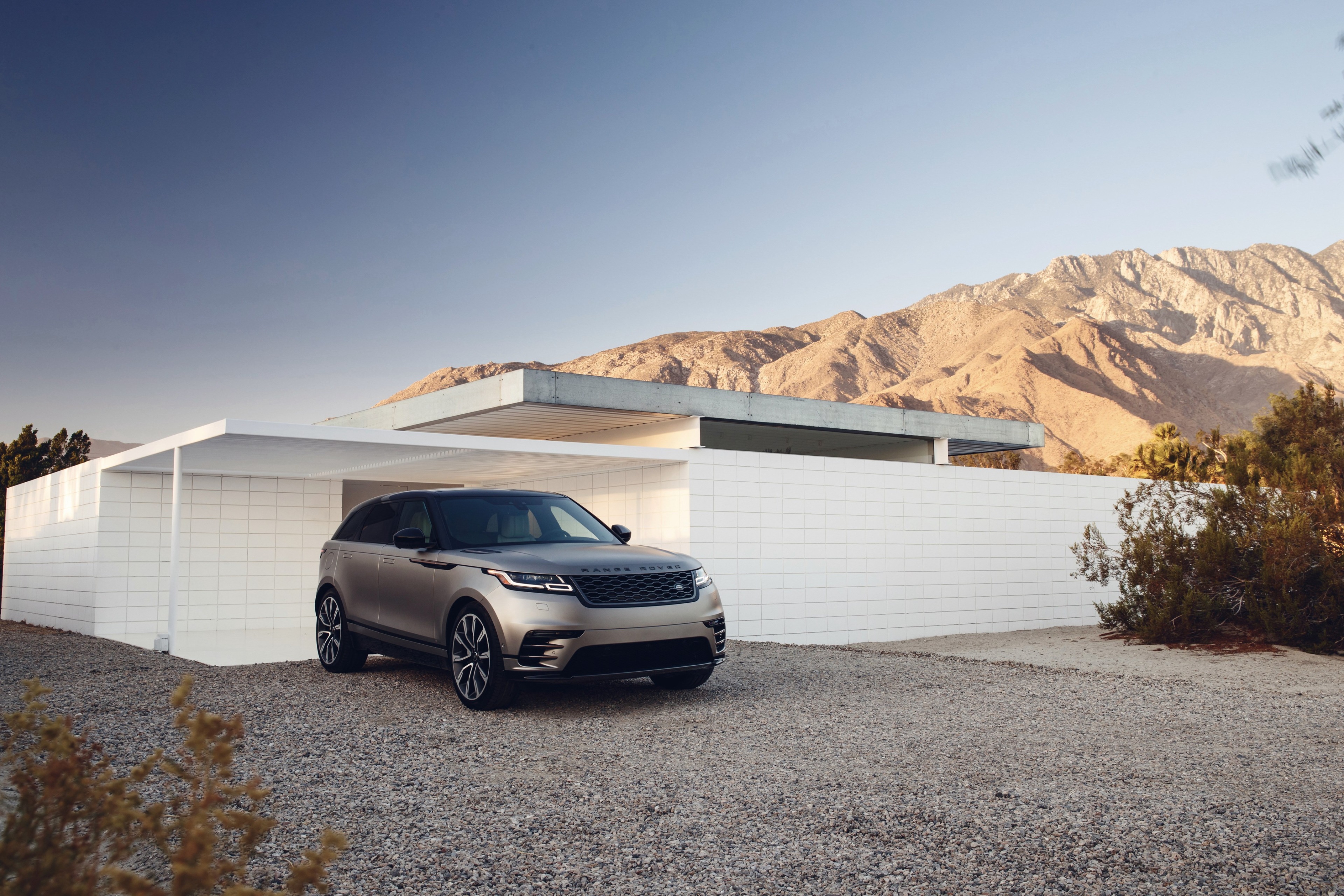 Range Rover Velar parked by modern house and mountains HD Wallpaper