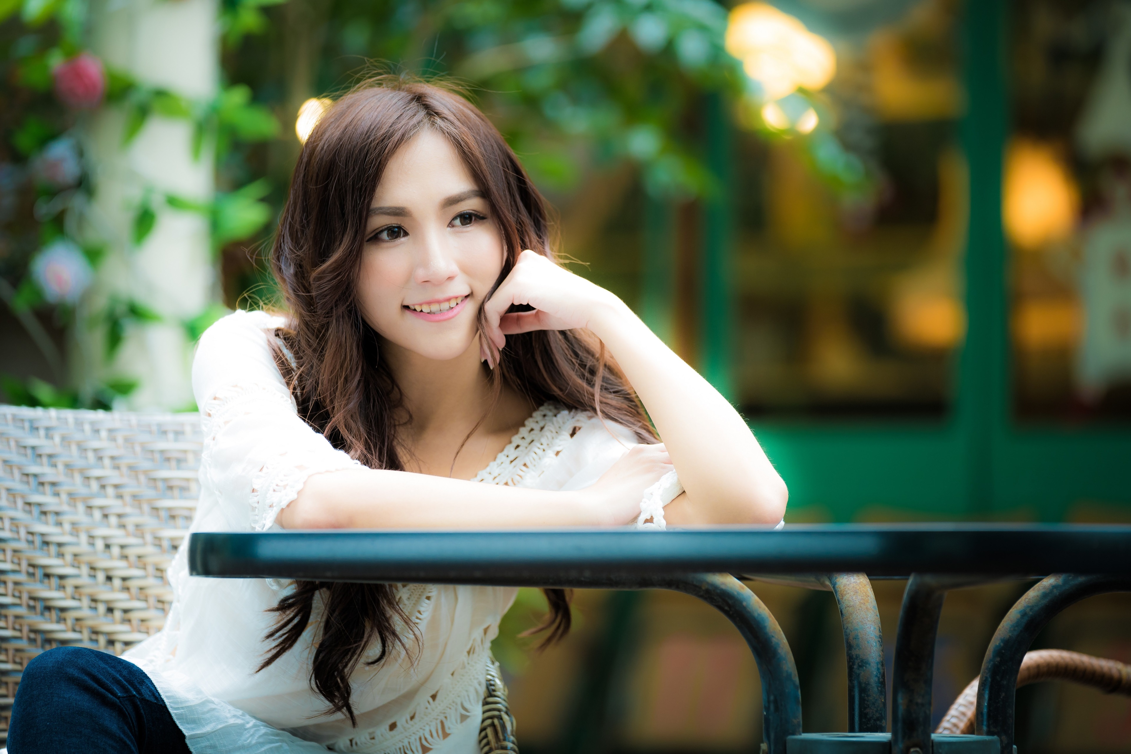 Asian woman sitting at a table outdoors HD Wallpaper