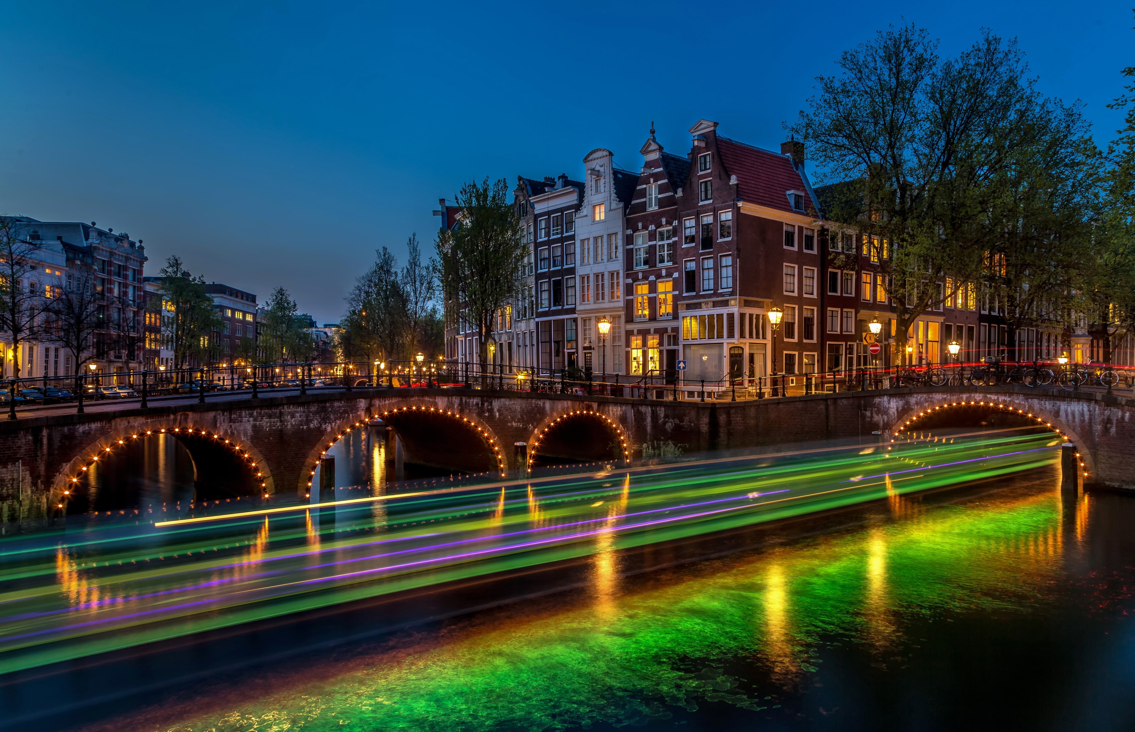 Amsterdam canal bridge at dusk with boat light trails HD Wallpaper