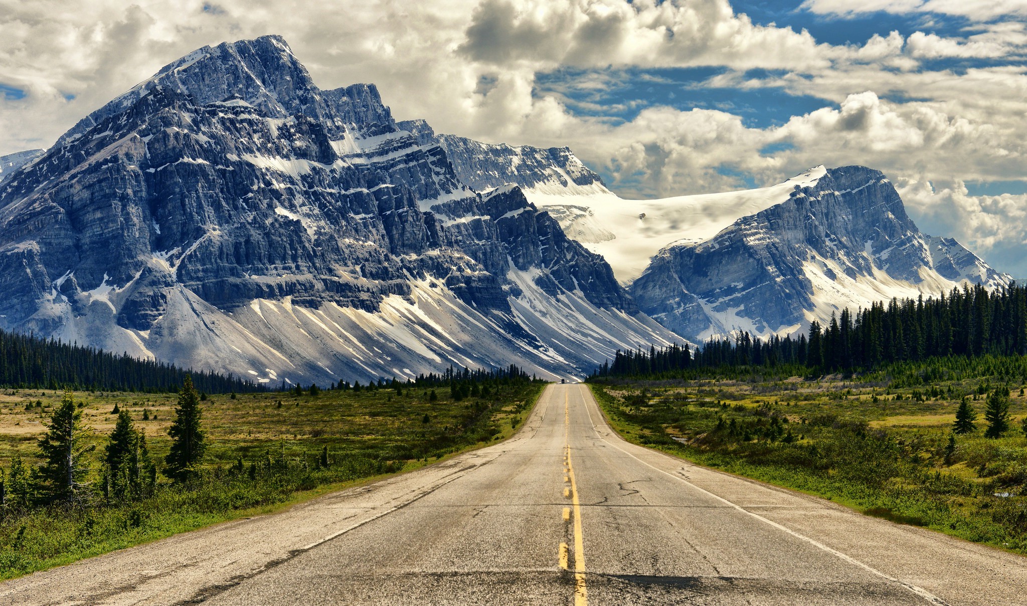 Road leading to snow-capped mountains HD Wallpaper