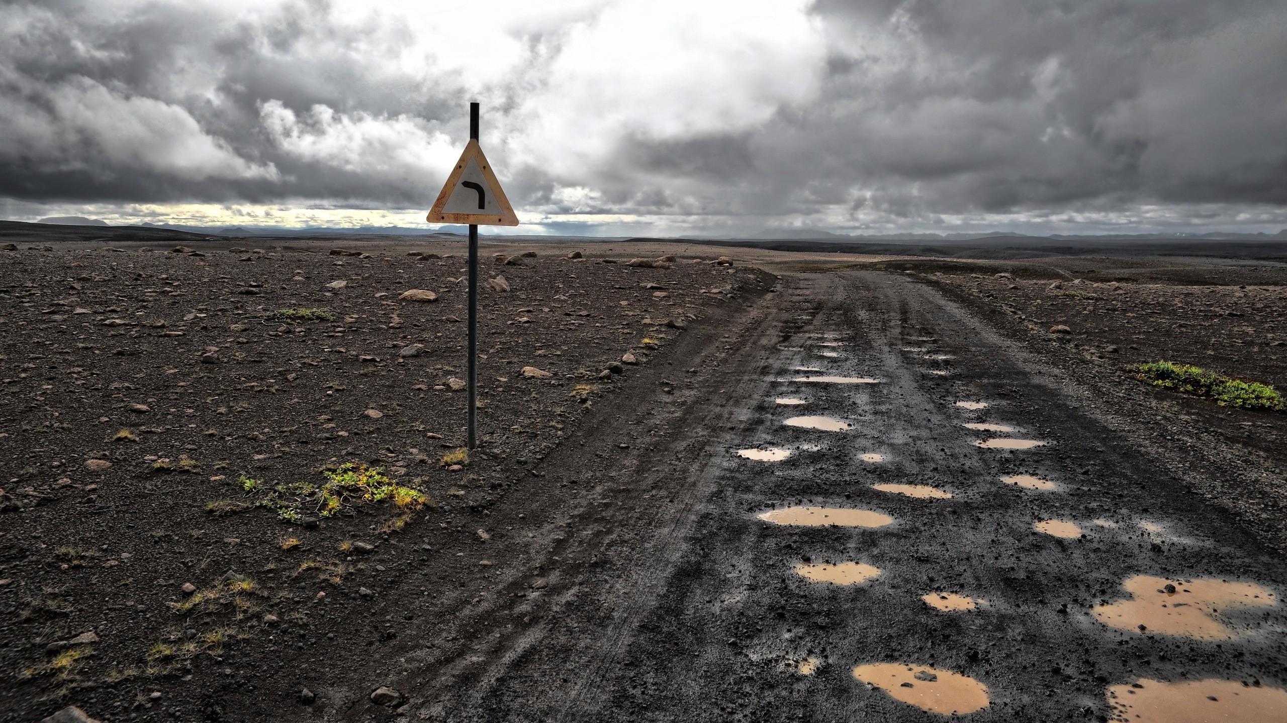 Road sign on a muddy road in a desolate landscape HD Wallpaper