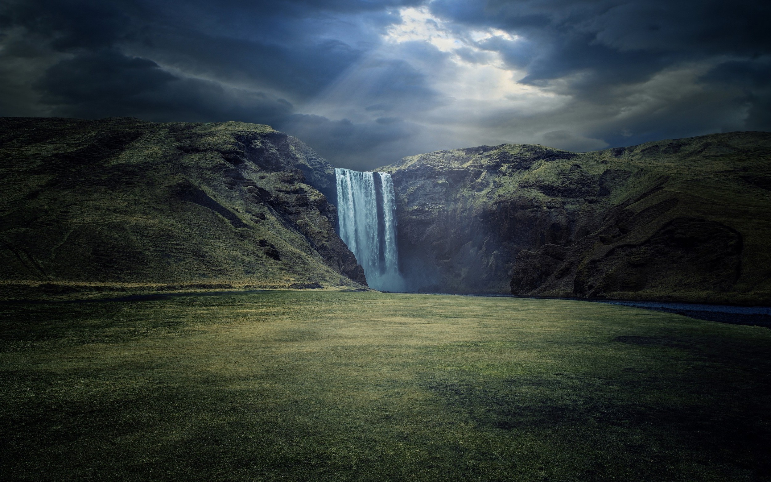 Waterfall in Iceland with Sun Rays and Dark Clouds HD Wallpaper