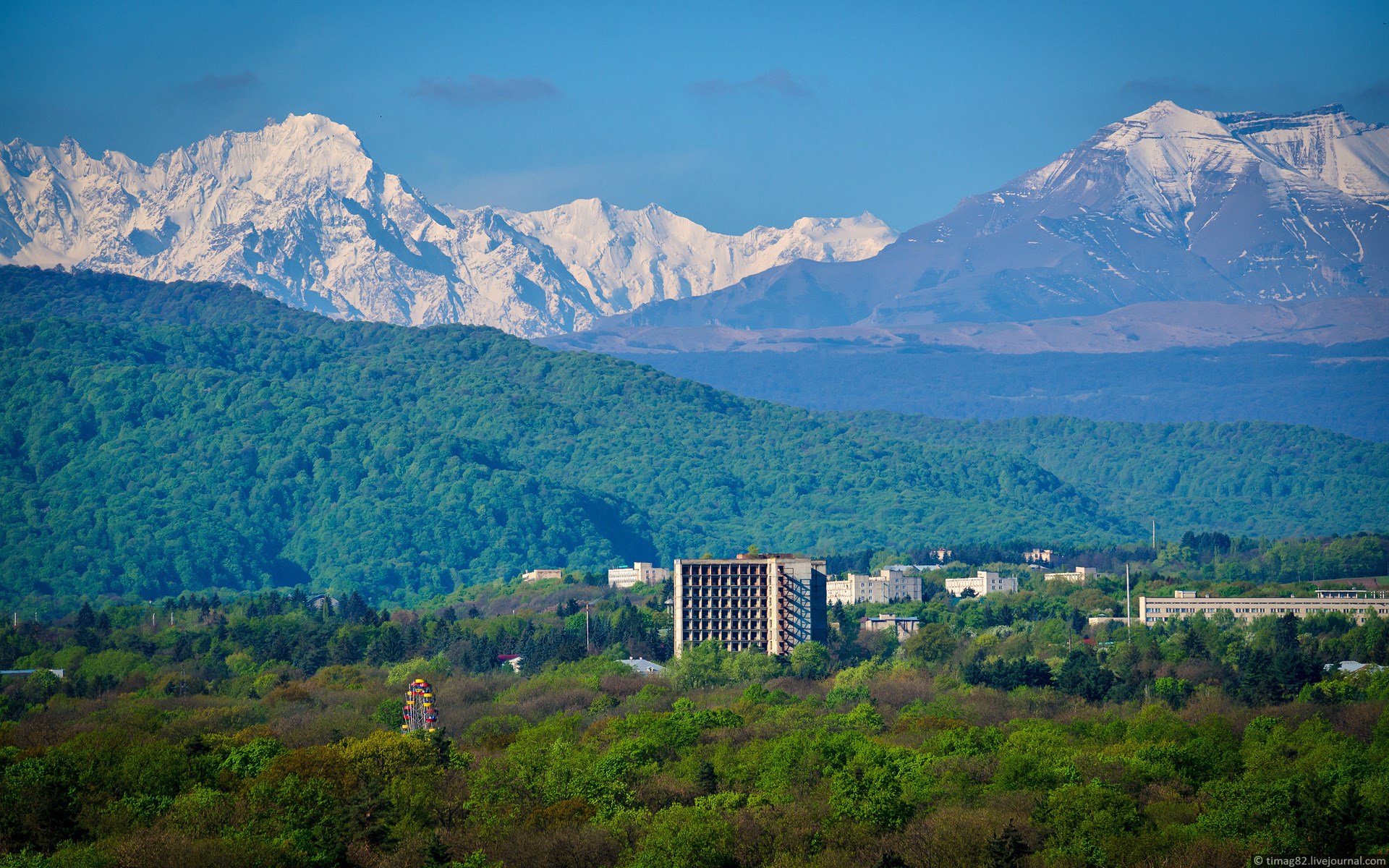 Snow-capped mountains and a forest town HD Wallpaper