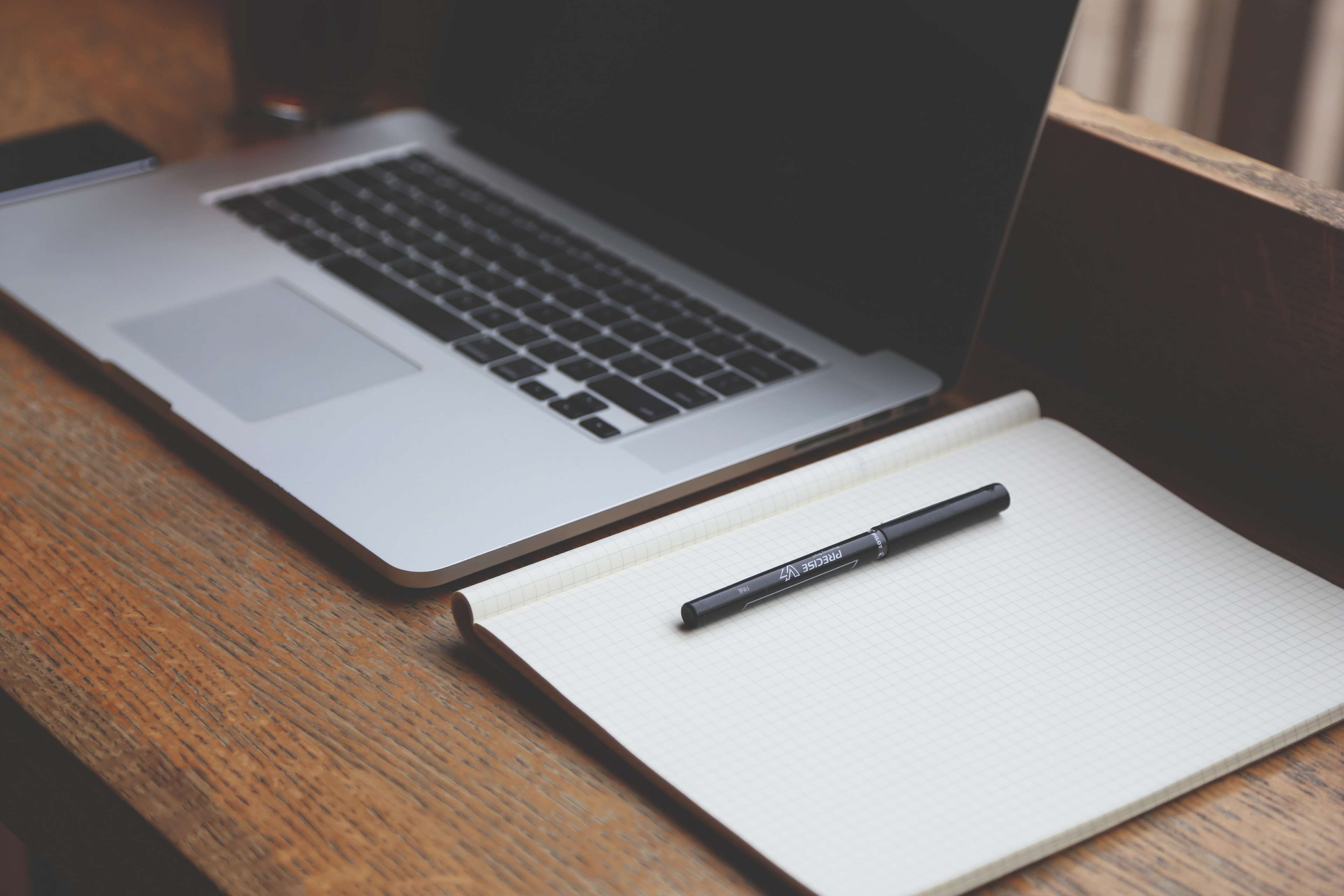 MacBook laptop and notebook on a wooden desk HD Wallpaper