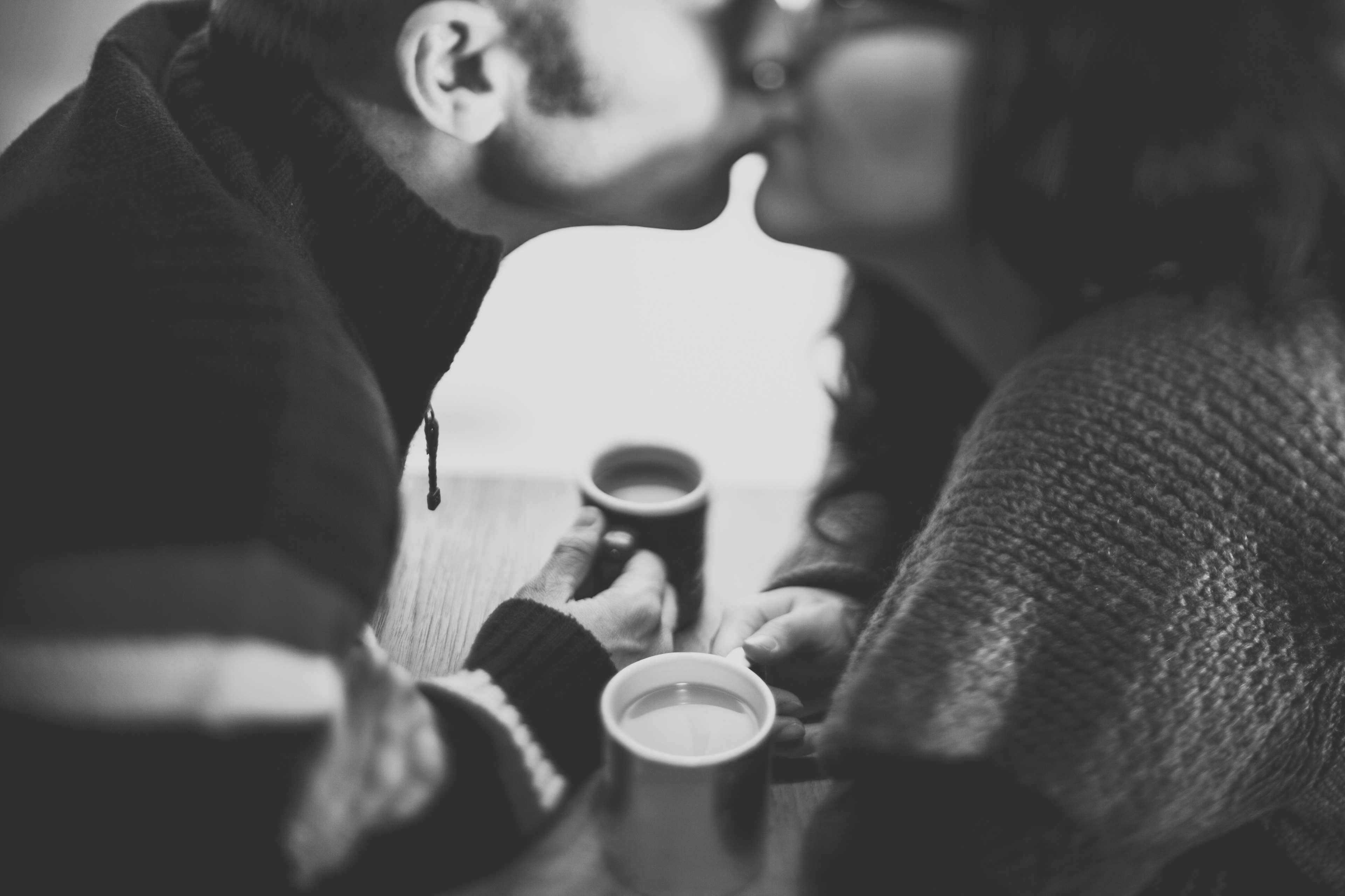 Couple kissing over coffee cups HD Wallpaper