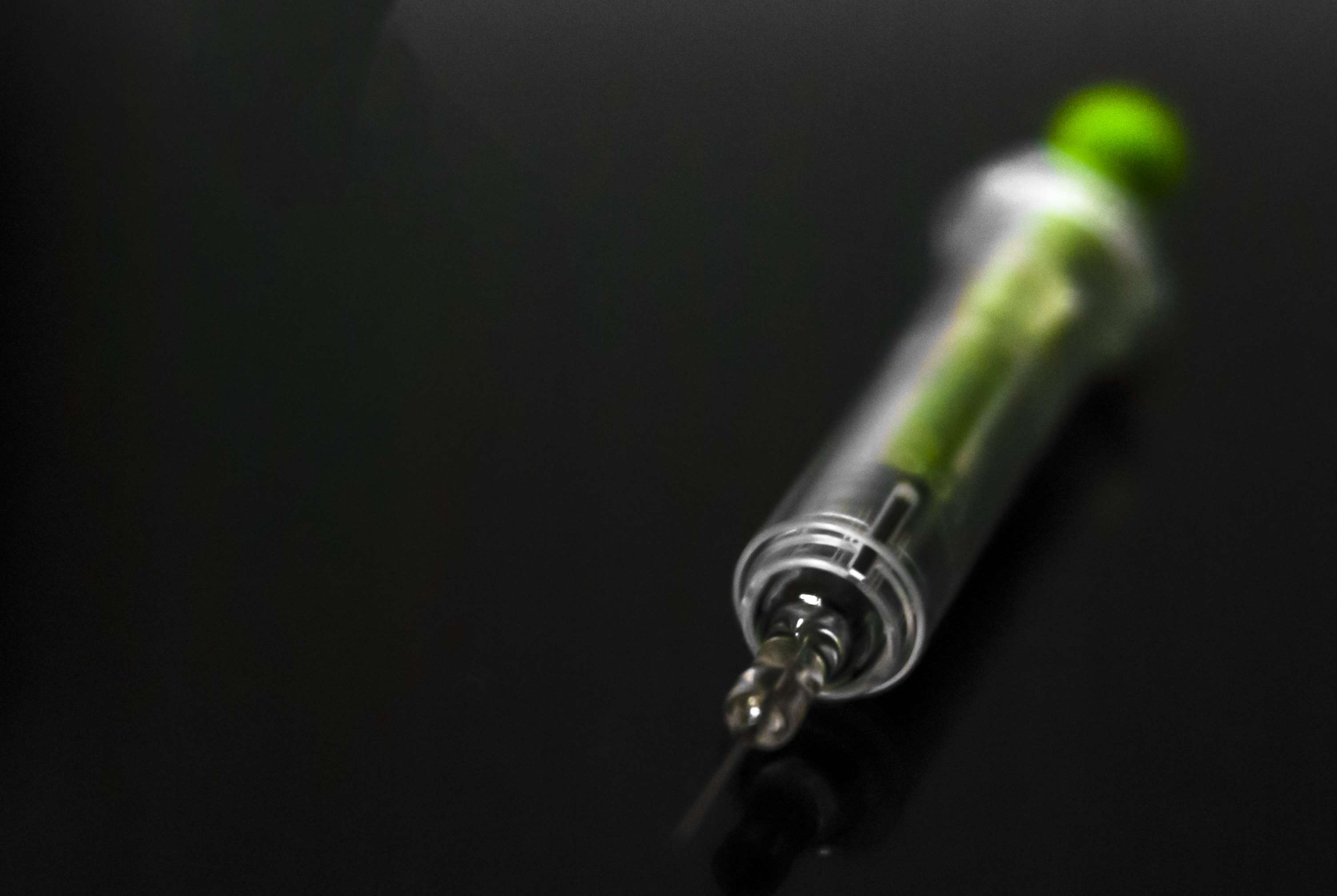 Close up of a syringe with green liquid HD Wallpaper