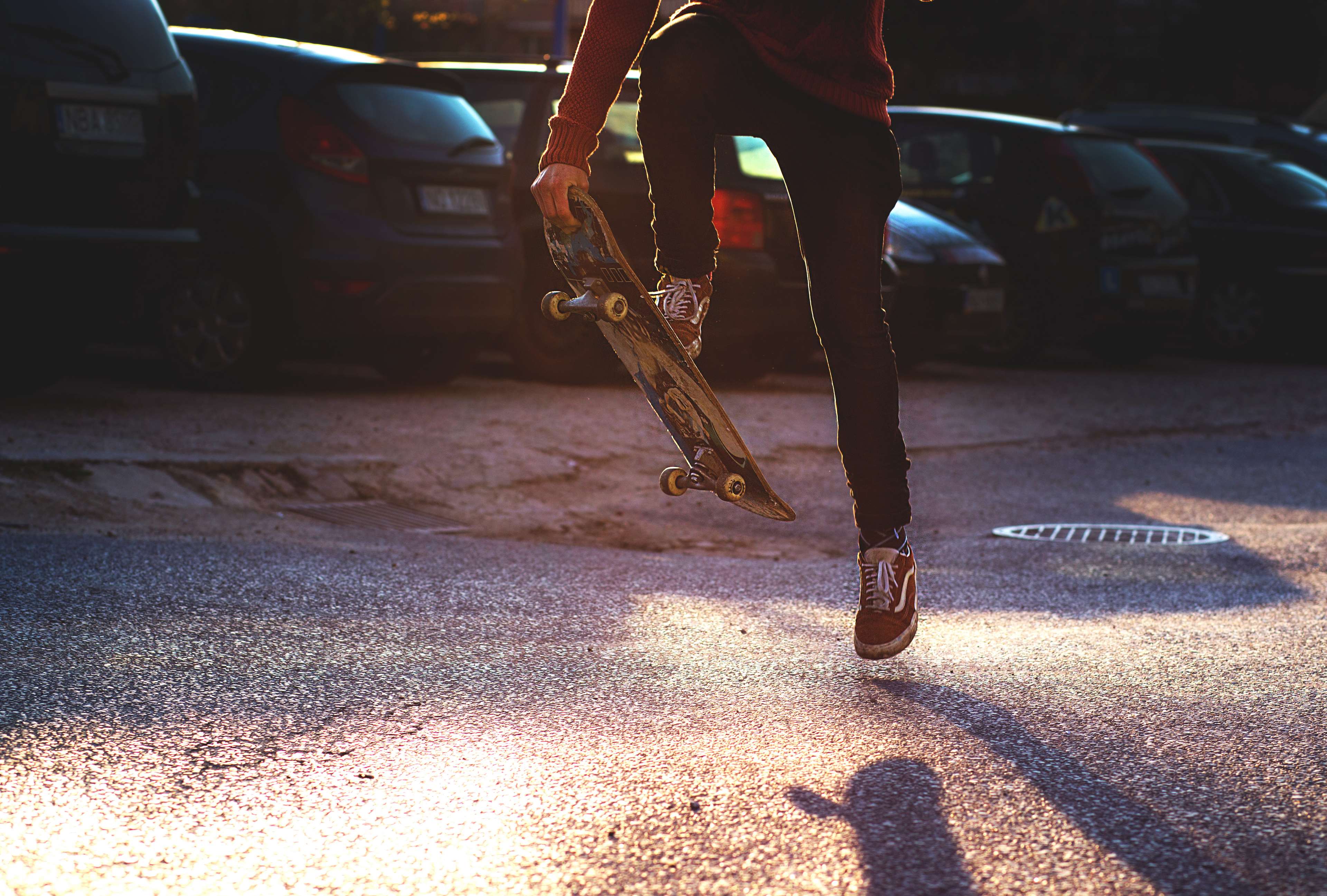 Person holding a skateboard in a parking lot 4K HD Wallpaper