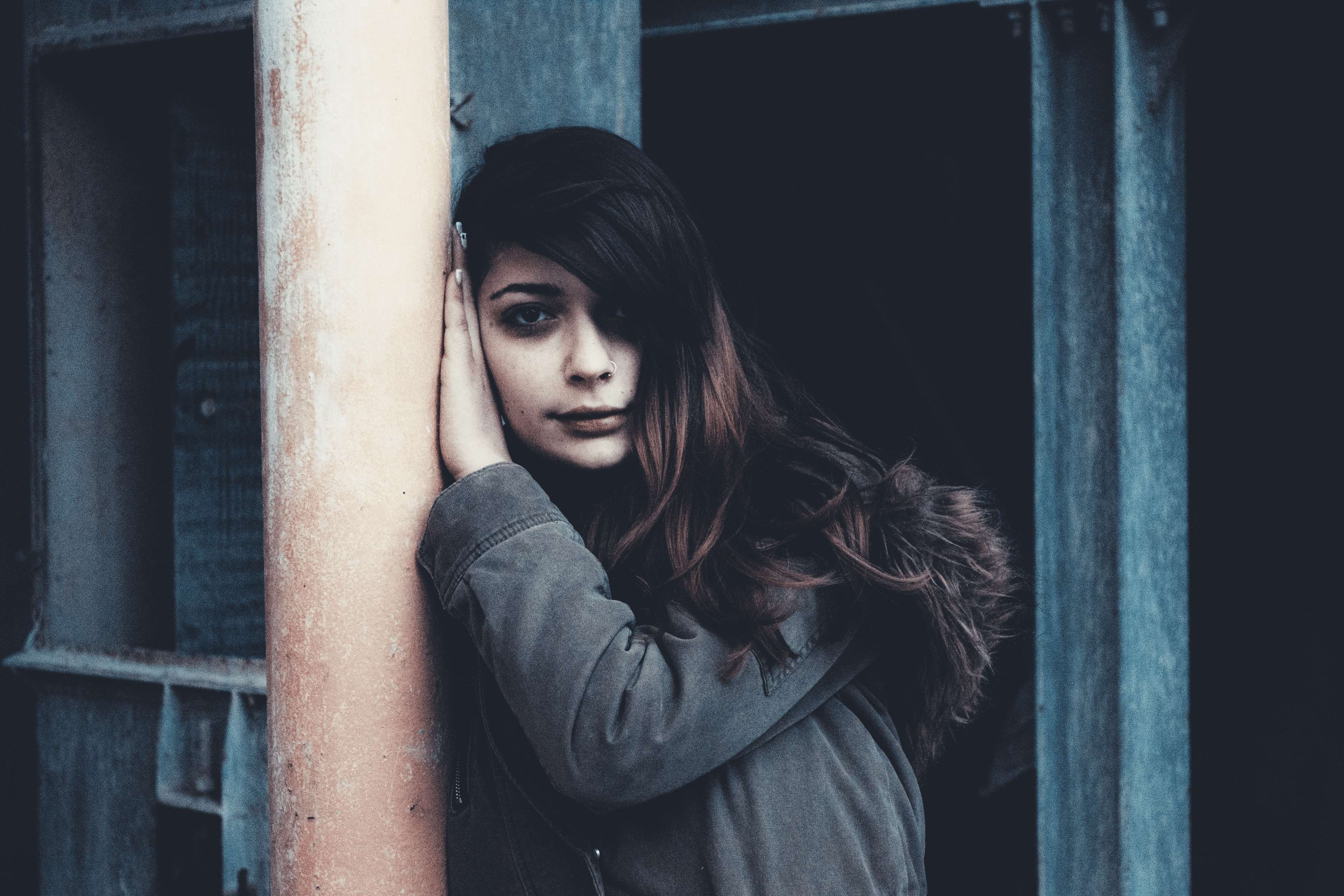 Young woman leaning against a pole HD Wallpaper