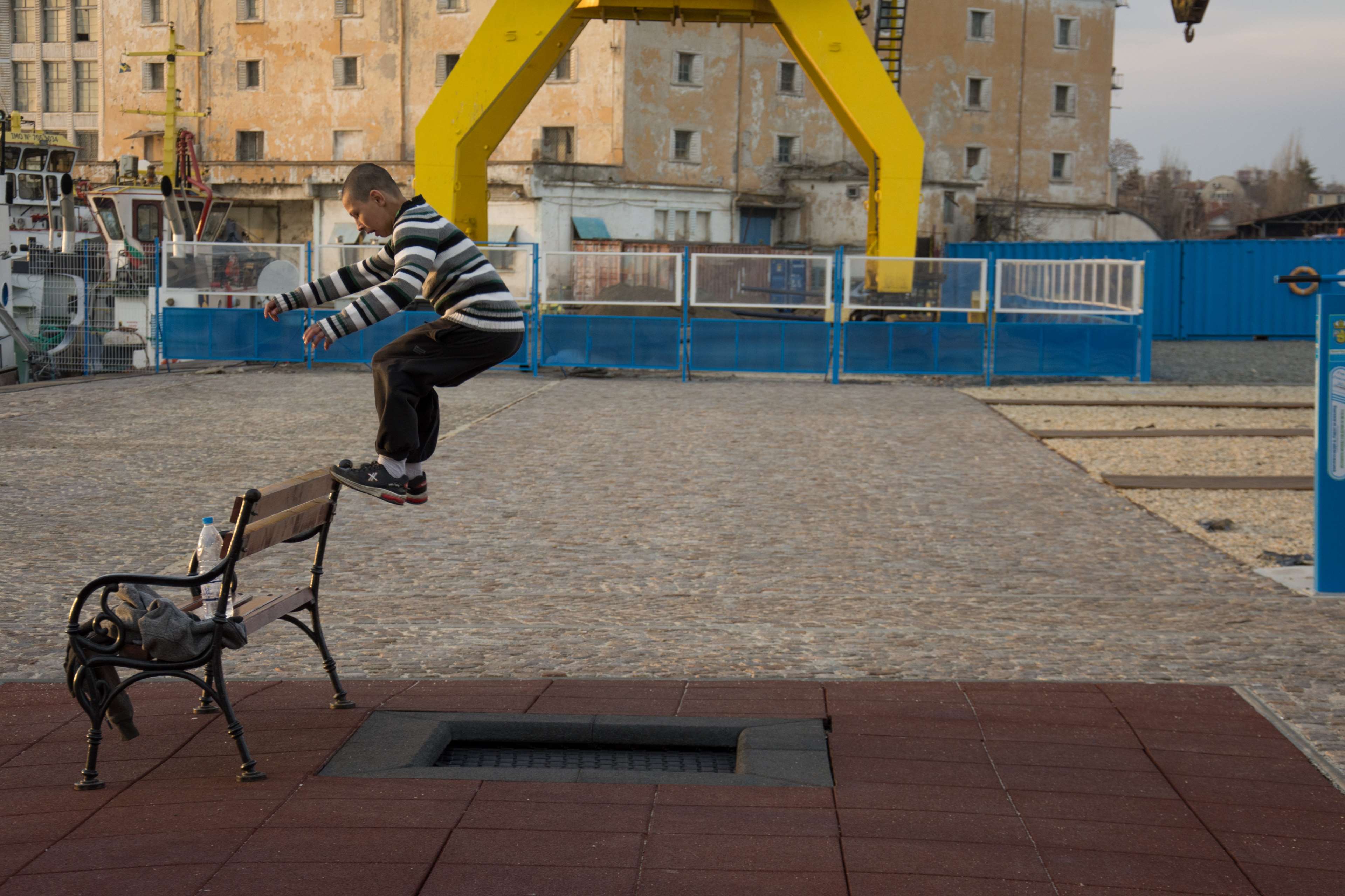 Boy jumping over a bench in an urban area HD Wallpaper
