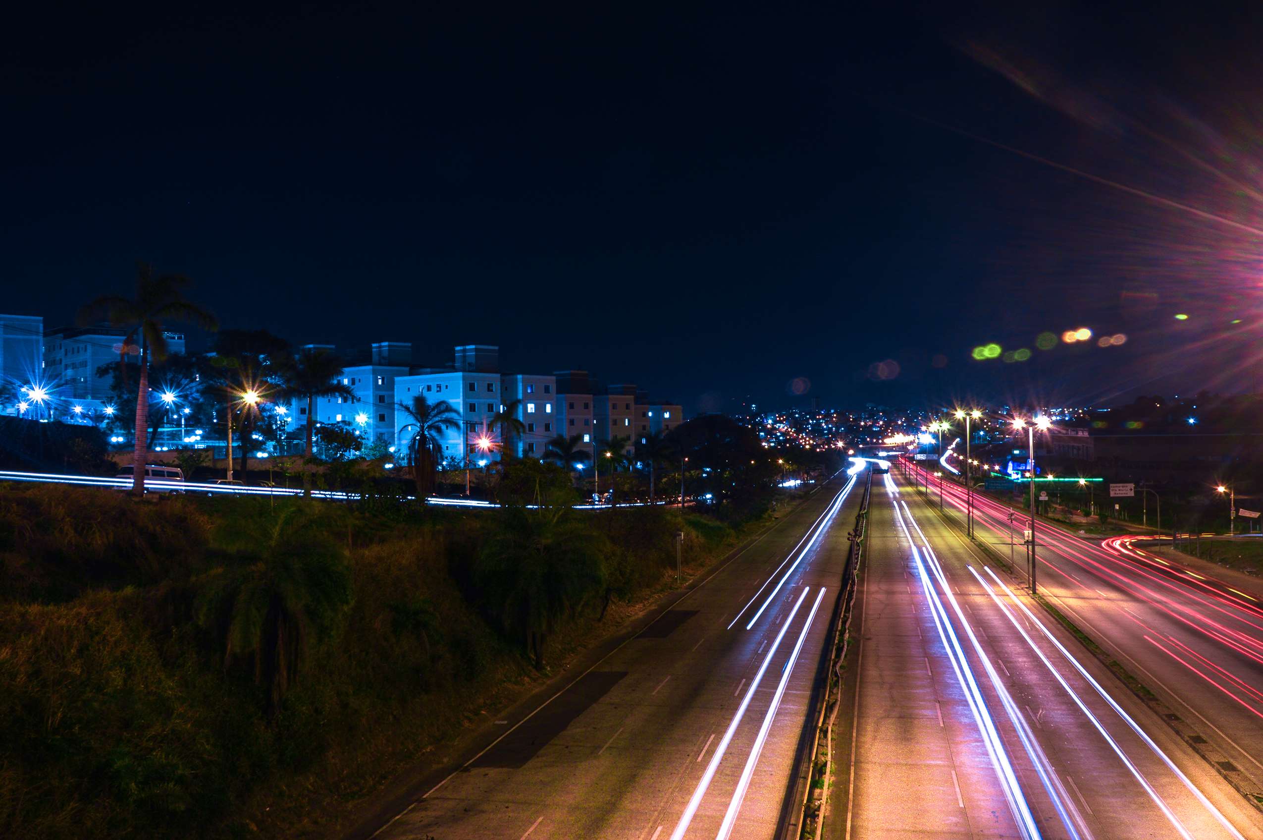 Long exposure of a highway at night with city lights HD Wallpaper