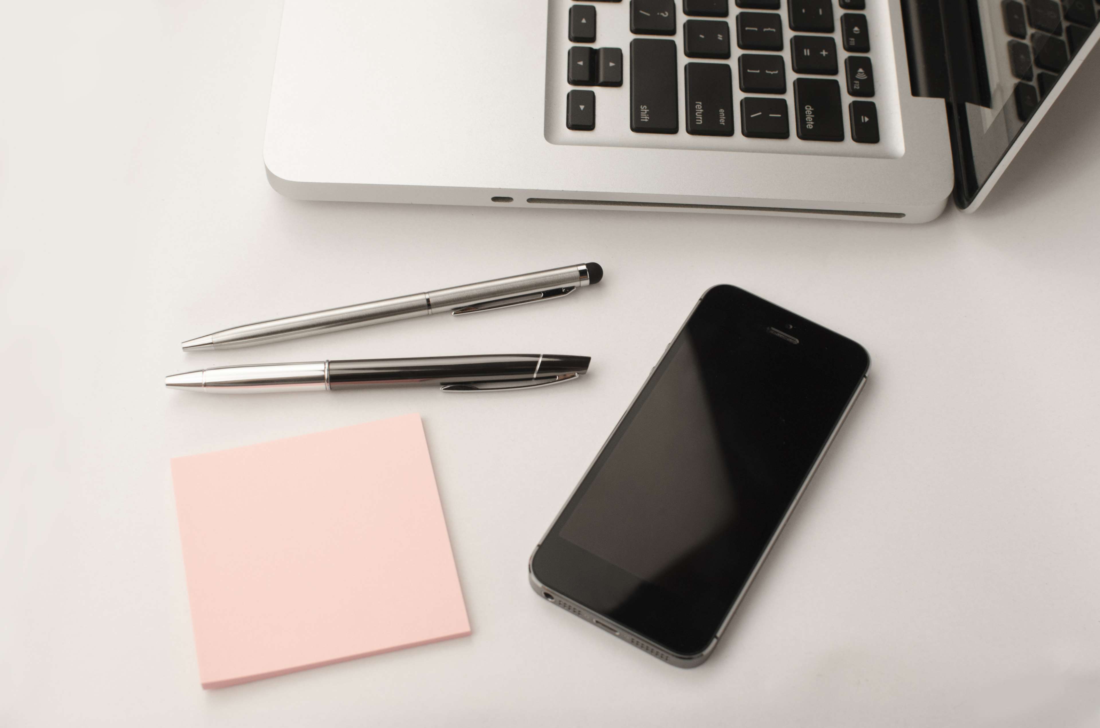 Laptop, smartphone, pens, and sticky note on a desk HD Wallpaper