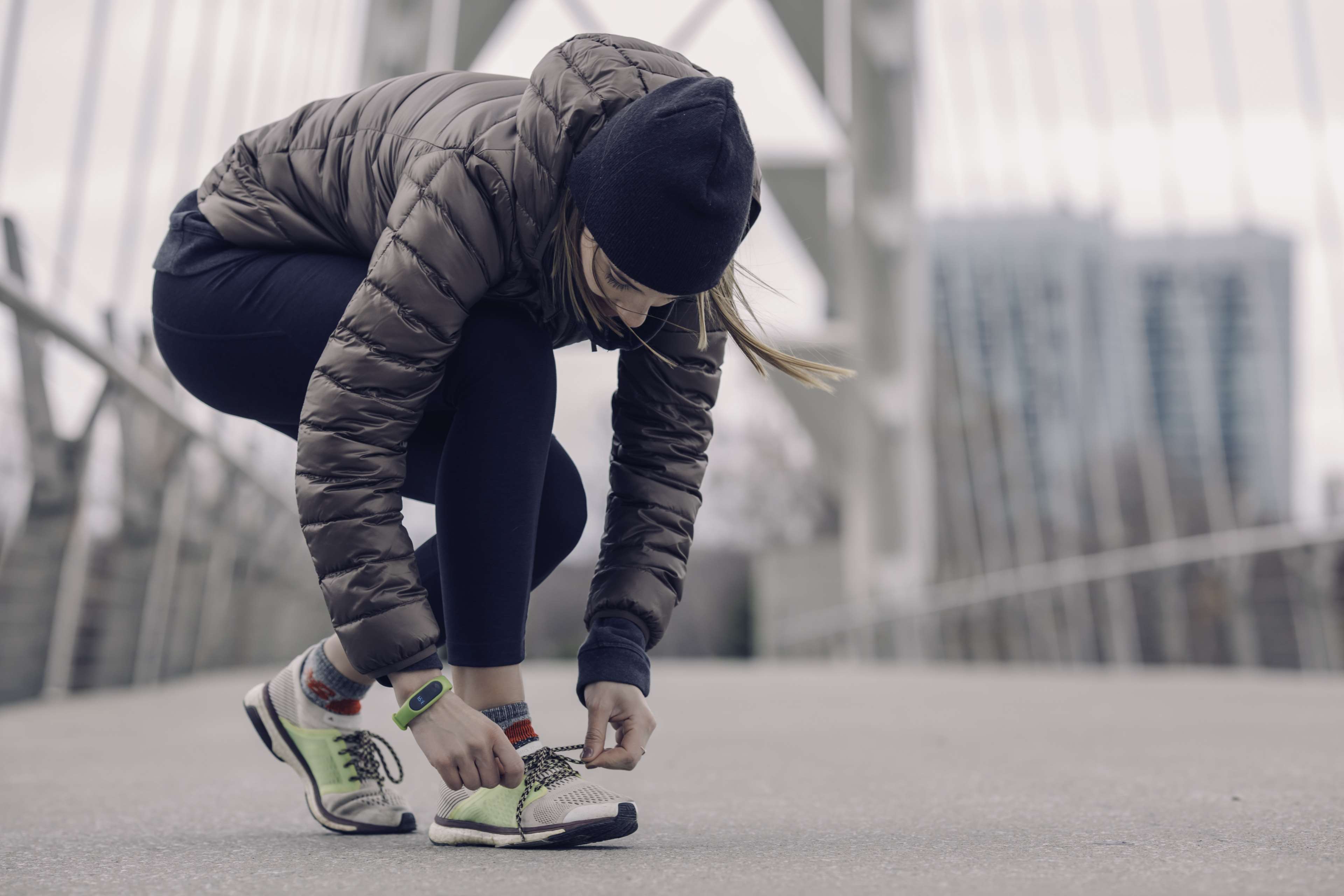 Woman tying shoelaces on a bridge in the city HD Wallpaper