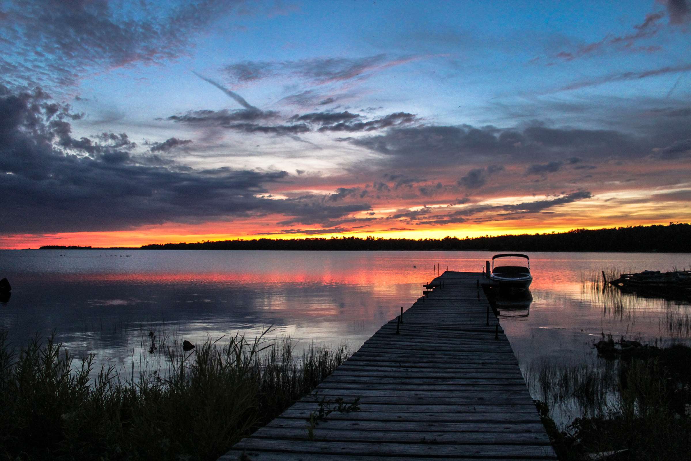 Wooden dock with boat at sunset on a lake HD Wallpaper