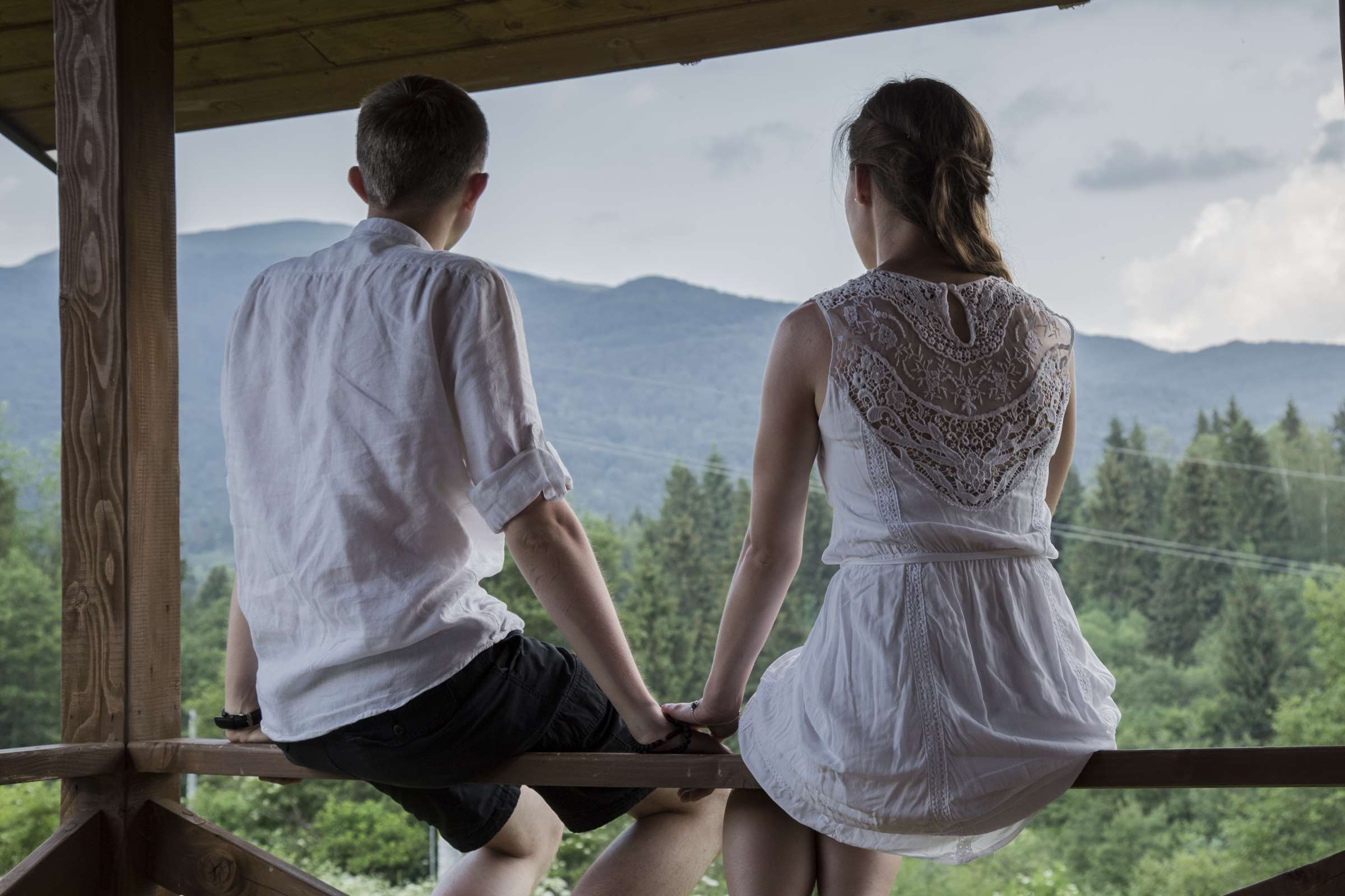 Couple holding hands on a balcony overlooking mountains HD Wallpaper