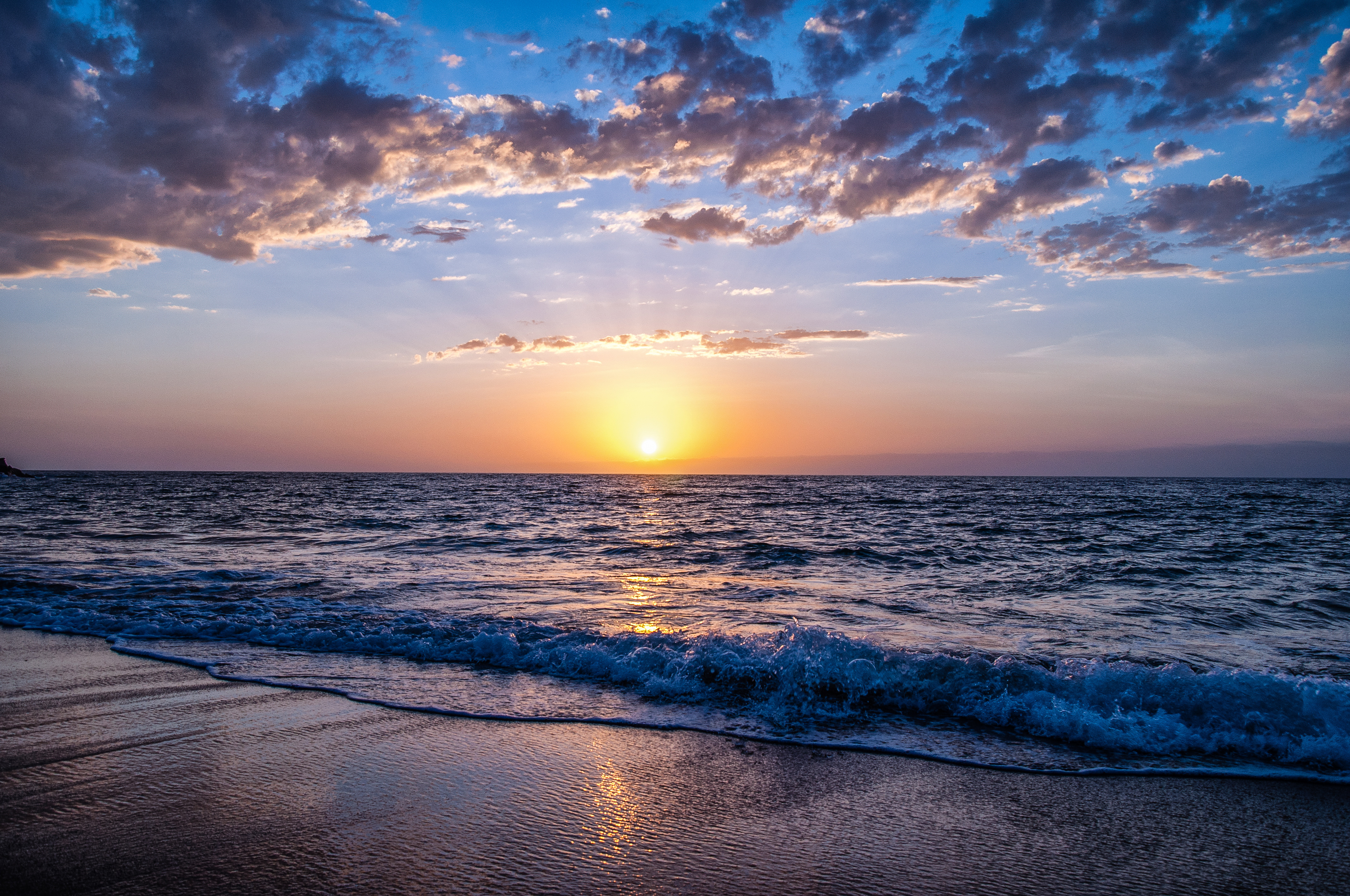 Sunset over the ocean with clouds and waves HD Wallpaper