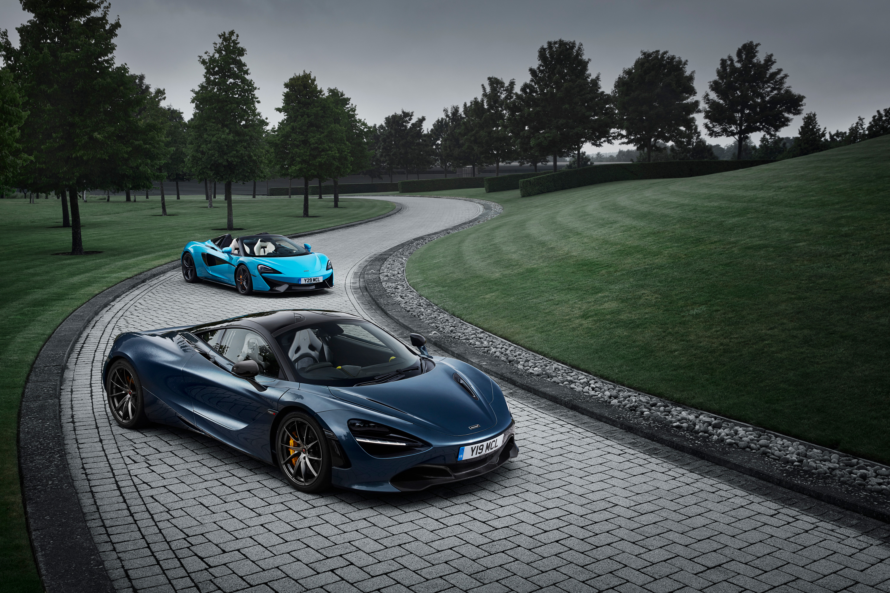 Two McLaren sports cars on a paved driveway HD Wallpaper