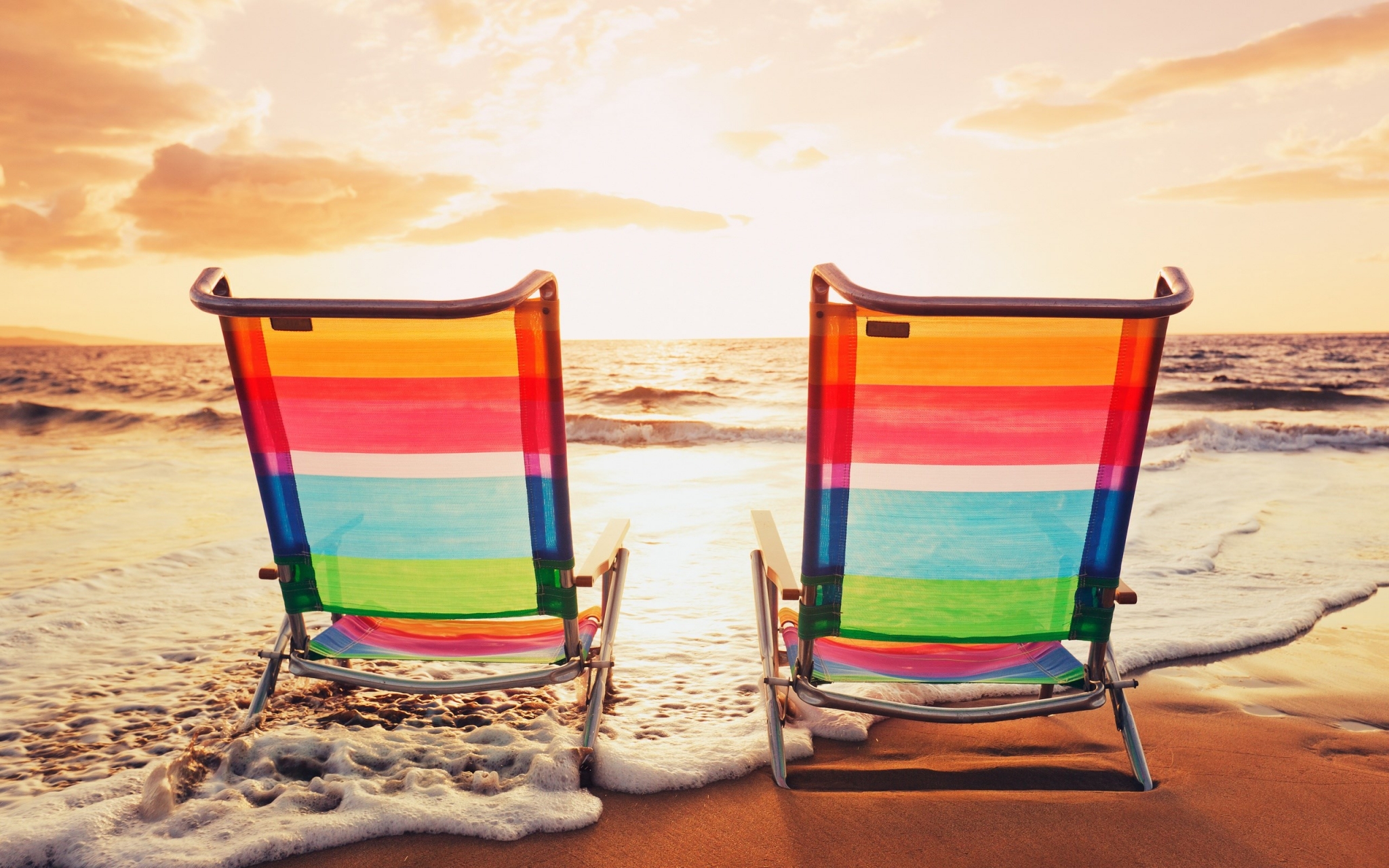 Two beach chairs on a sandy beach at sunset HD Wallpaper