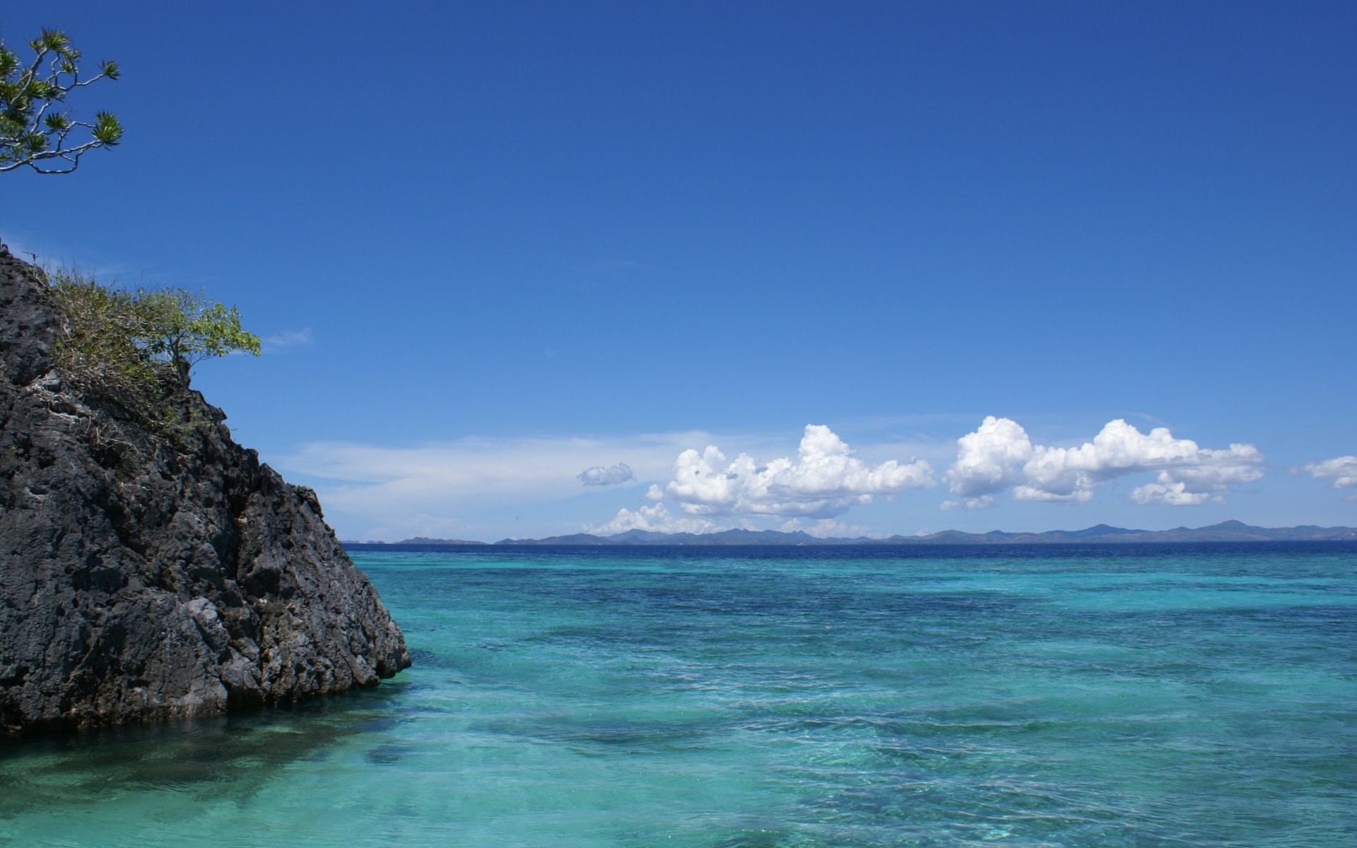 Rocky island and turquoise ocean under blue sky HD Wallpaper