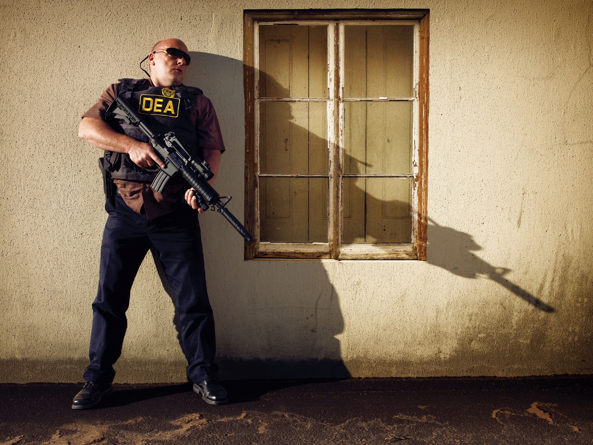 DEA agent with rifle in front of building HD Wallpaper