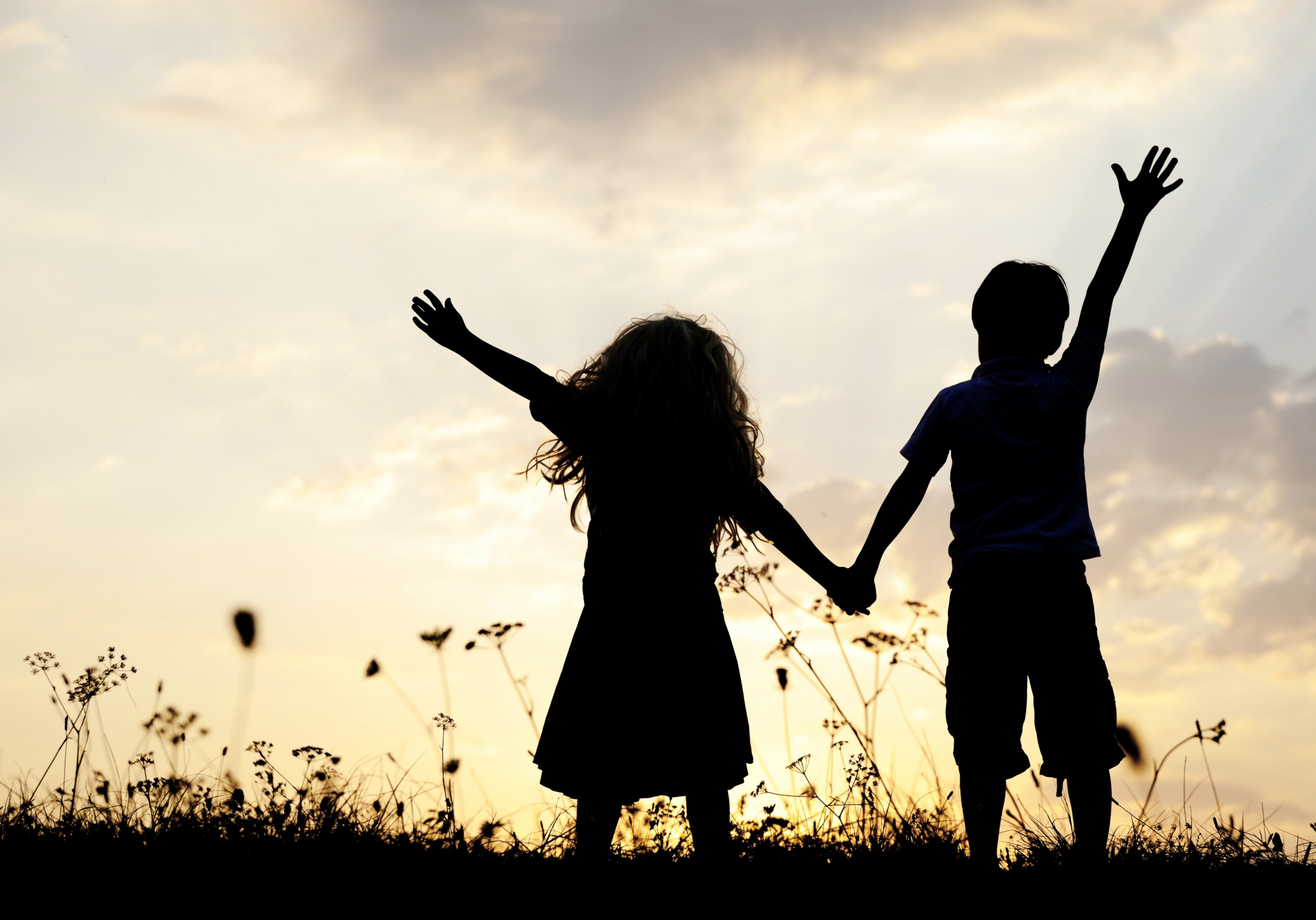 Two children holding hands at sunset HD Wallpaper