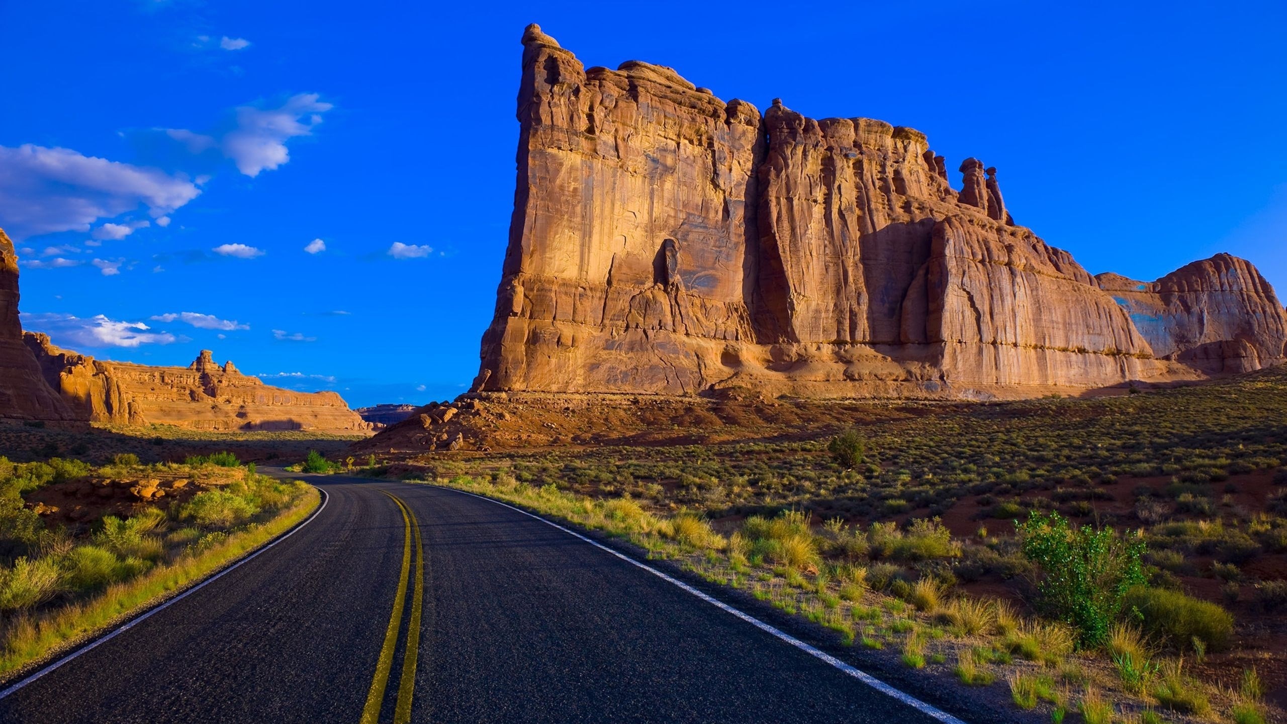 Road through Arches National Park with sandstone cliffs HD Wallpaper