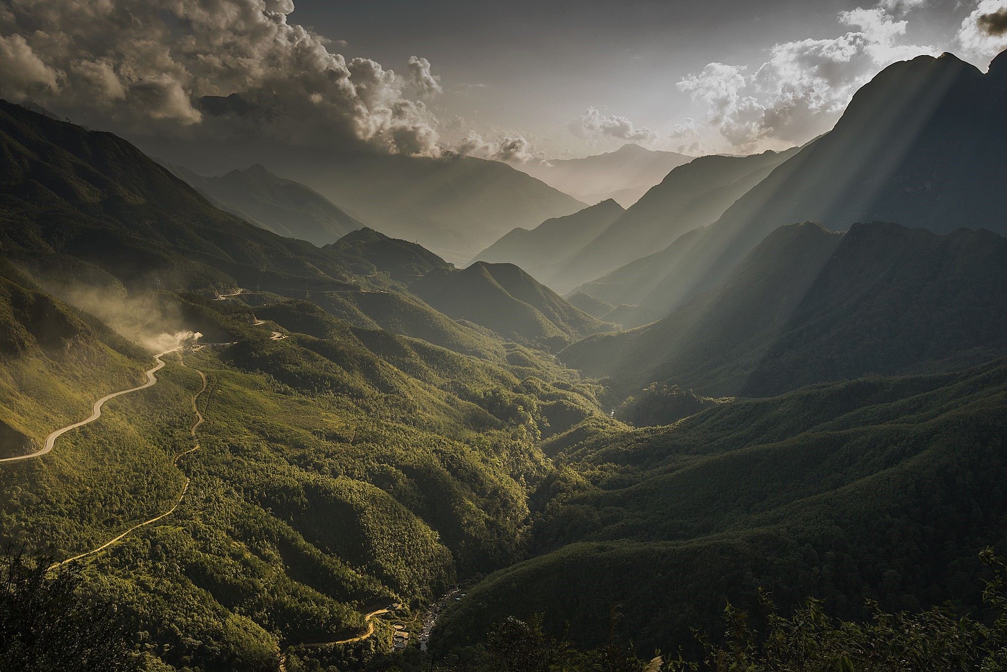 Mountain valley with winding road and sun rays HD Wallpaper